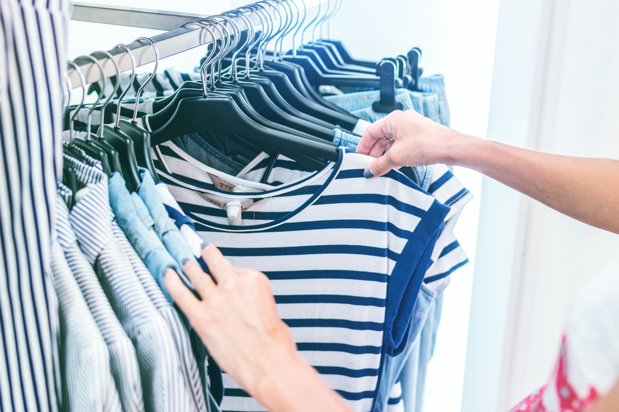 woman looking at t-shirts on rack in clothes shop