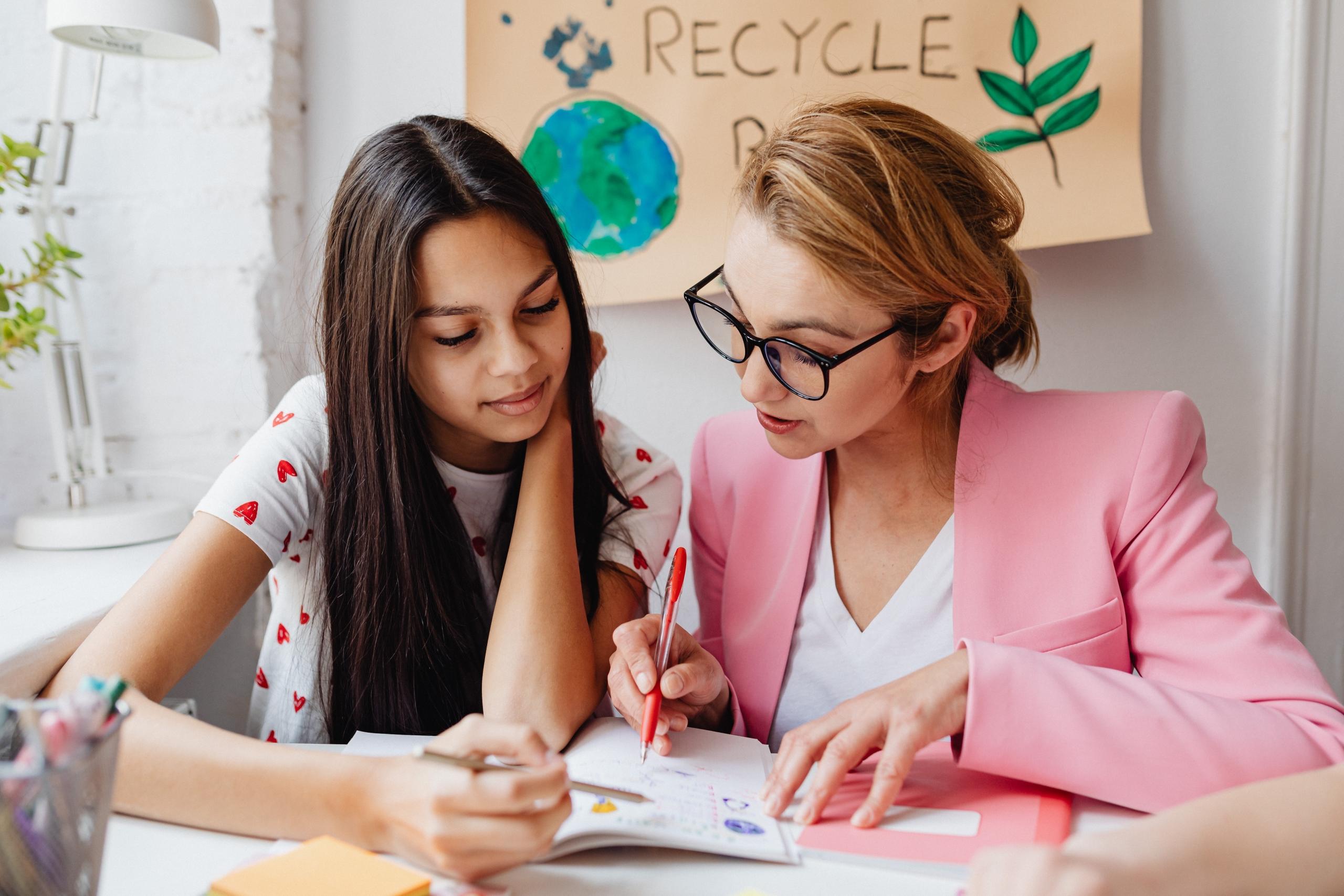 private teacher seated next to girl correcting her work