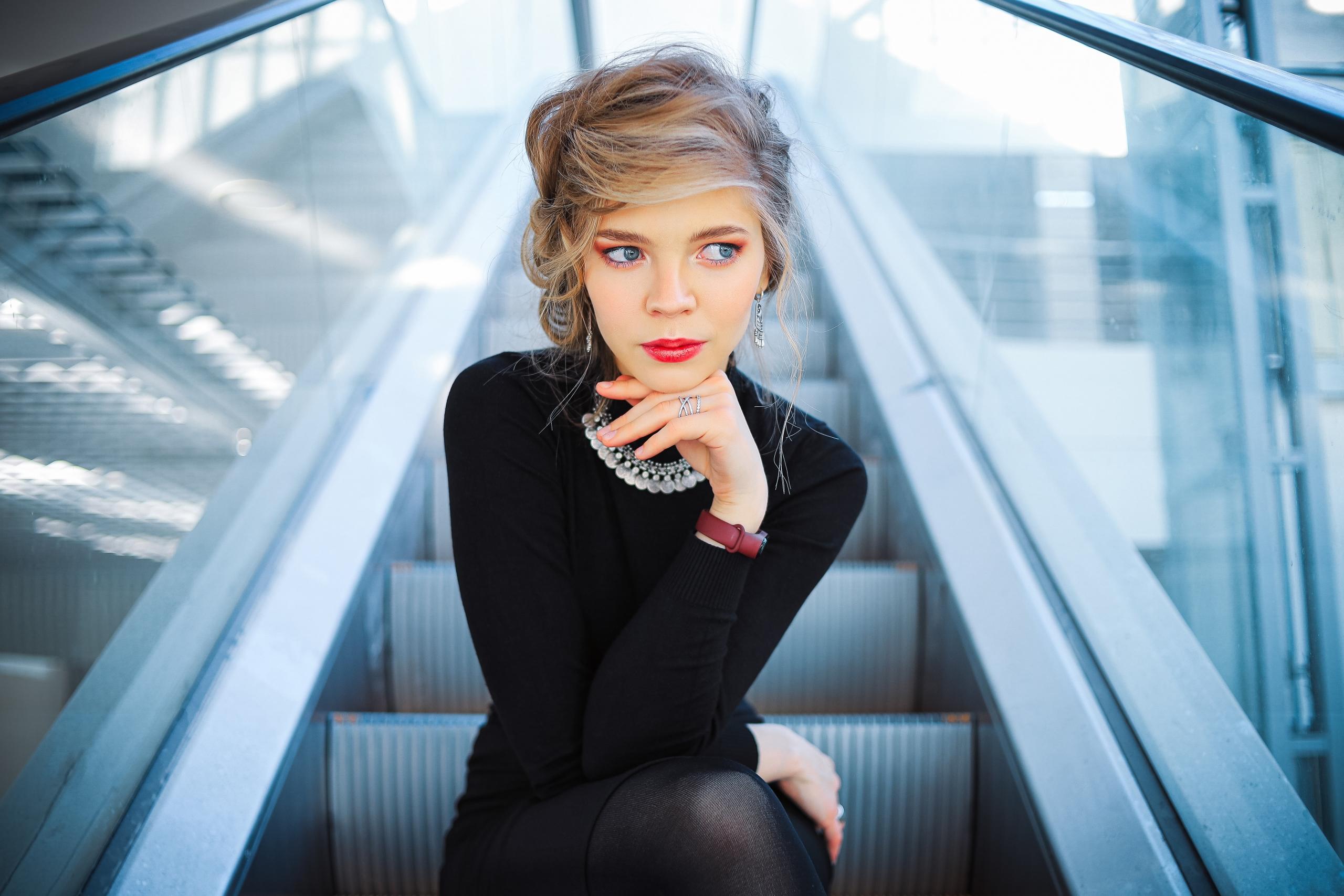 person wearing black clothes seated on escalator in shopping centre