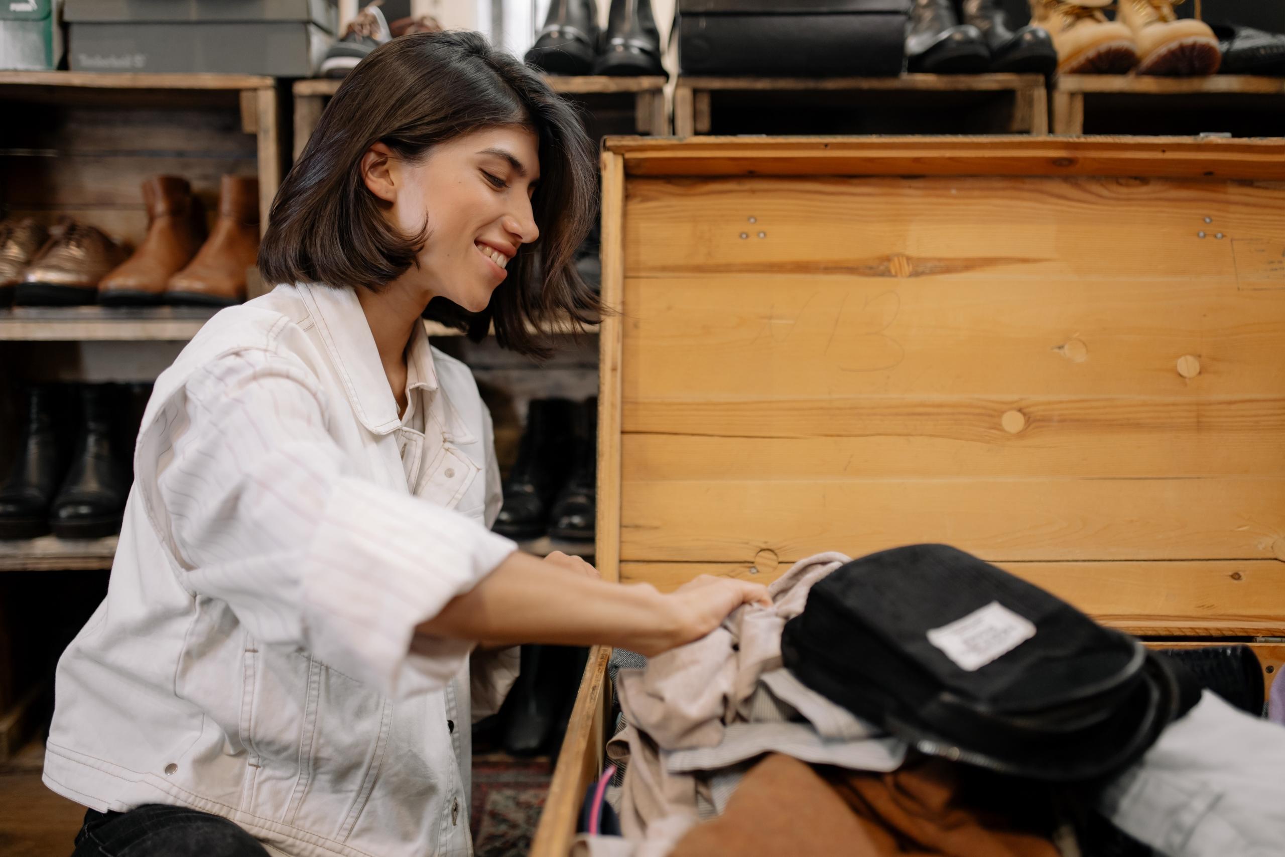 person rifling through a trunk of secondhand clothes