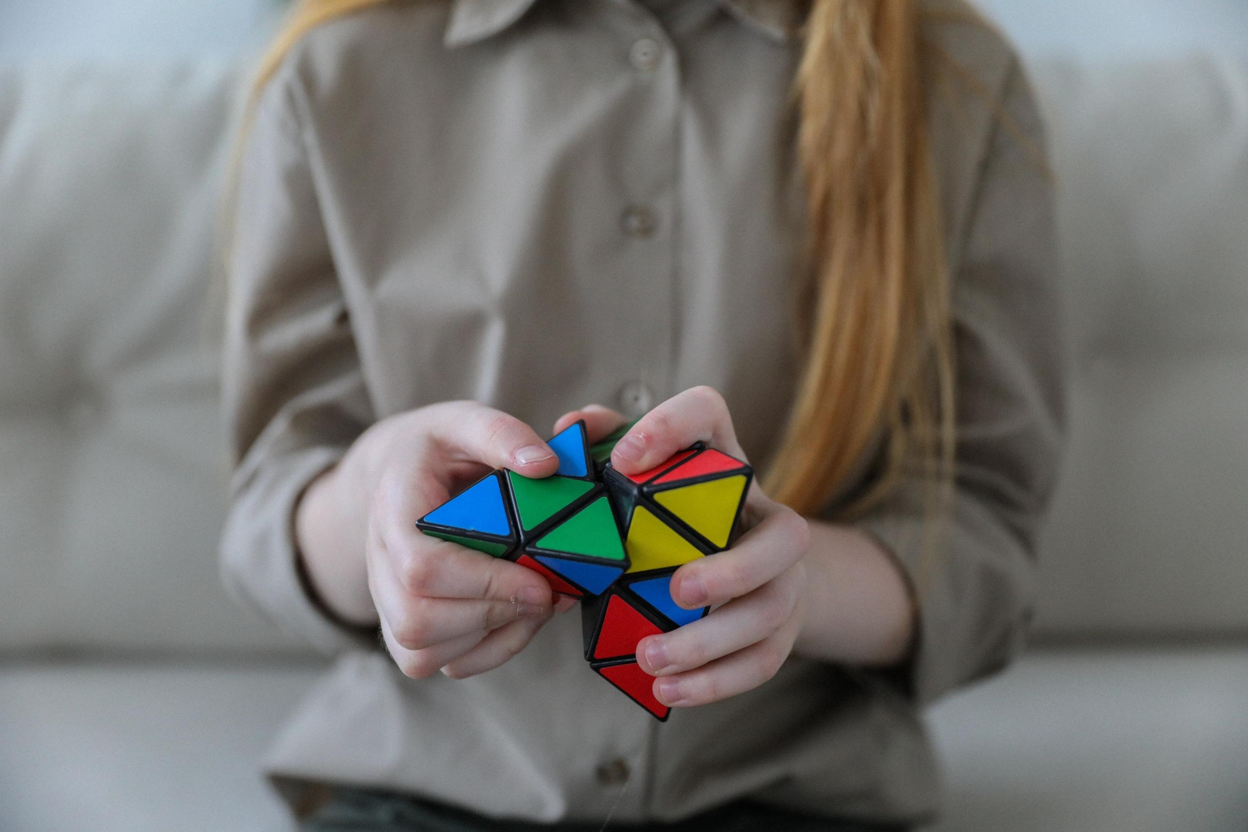 close up of girl's hands as she tries to solve Rubik's cube puzzle