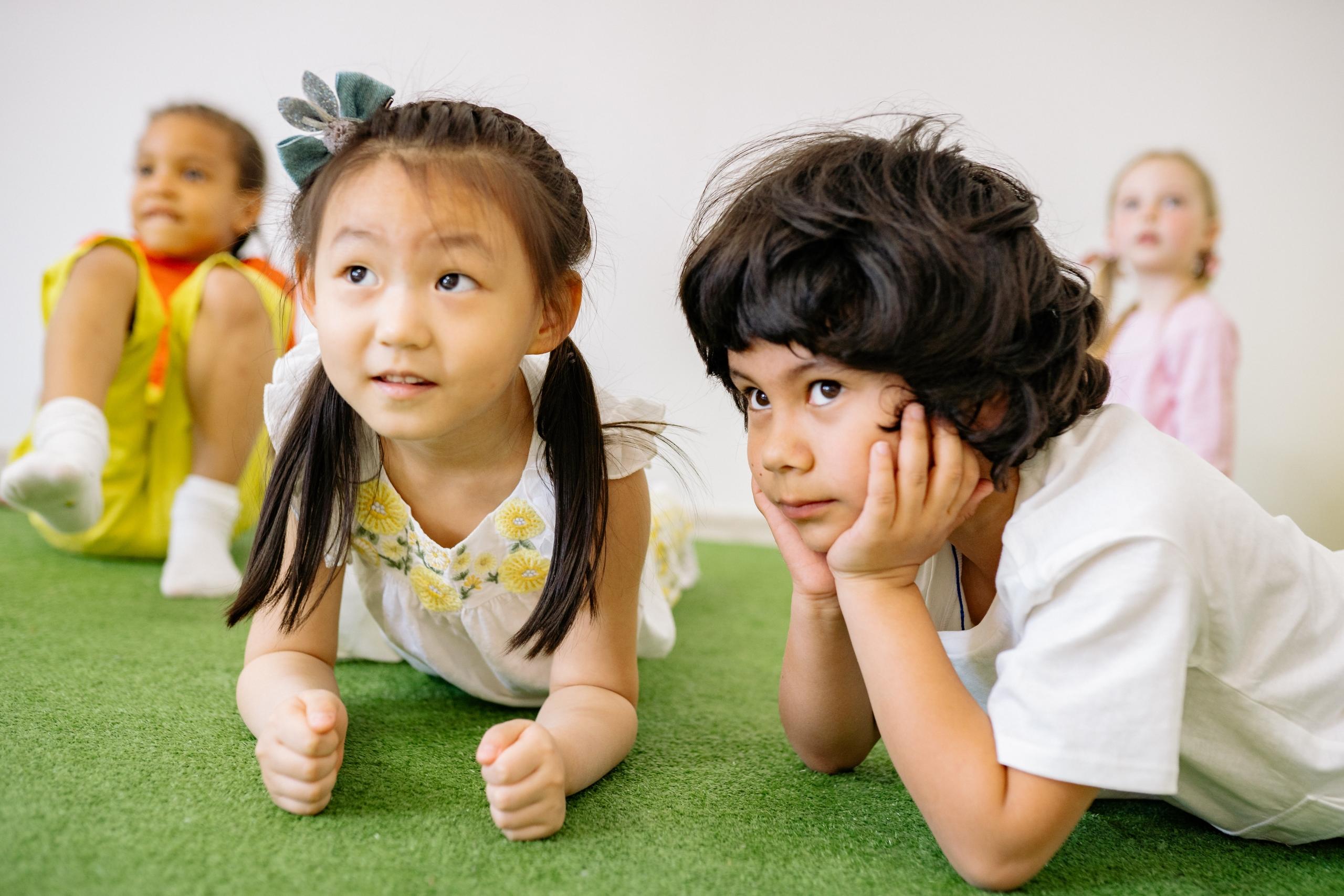 preschoolers playing on fake grass in classroom