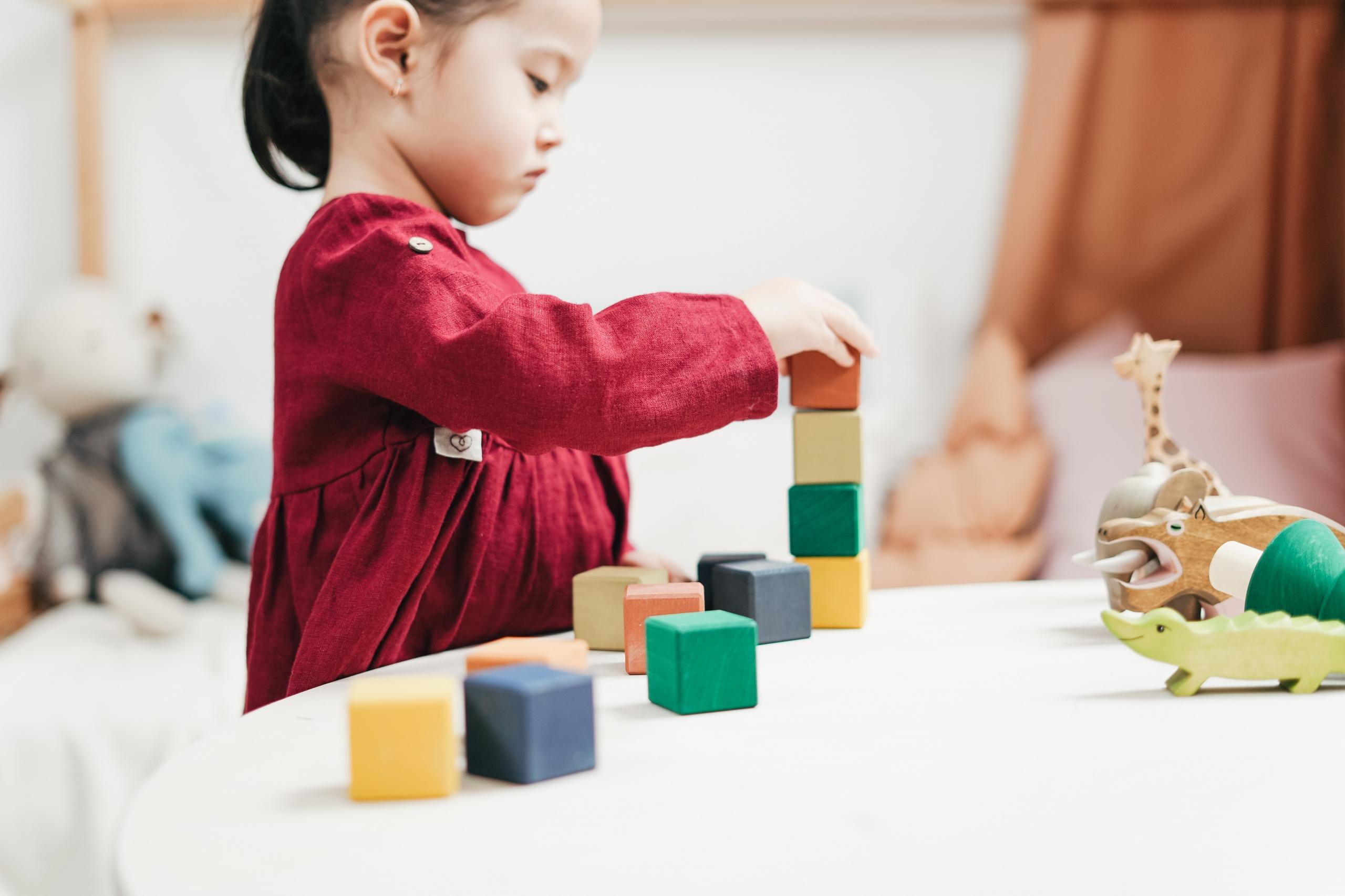 toddler building a tower with colourful wooden blocks