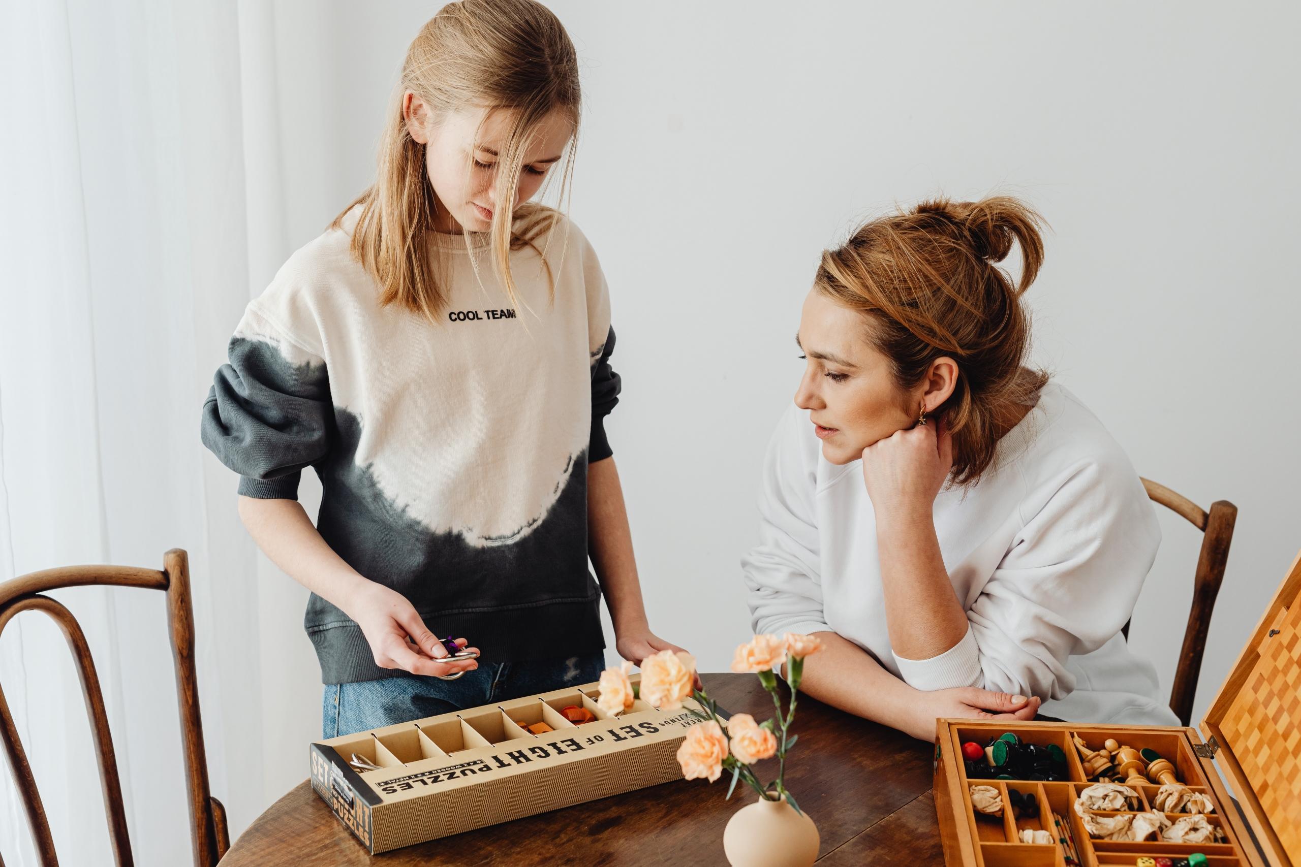 mom and daughter around table unpacking pieces of boardgame
