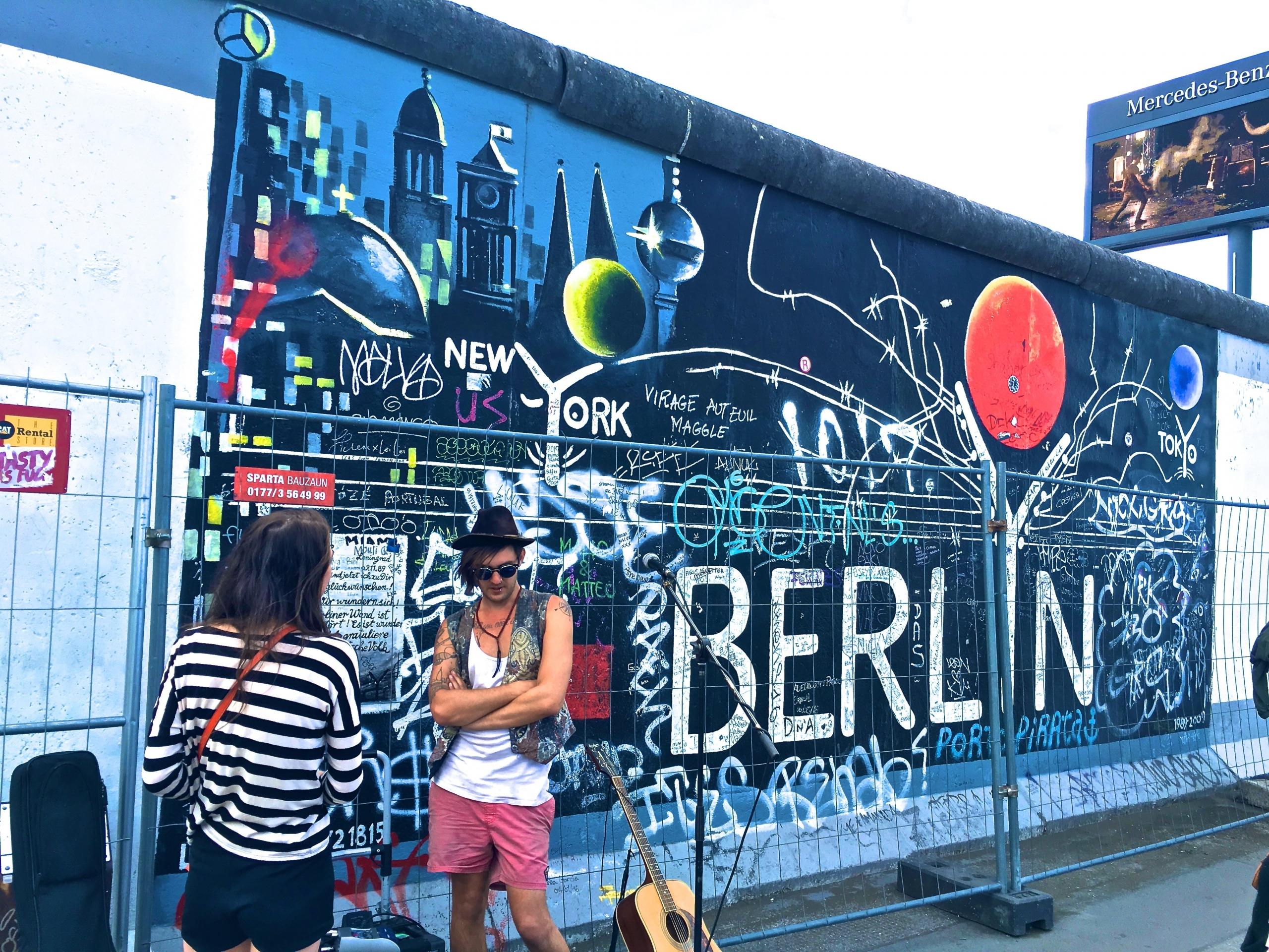 man and woman standing in front of graffitied wall in Berlin, Germany