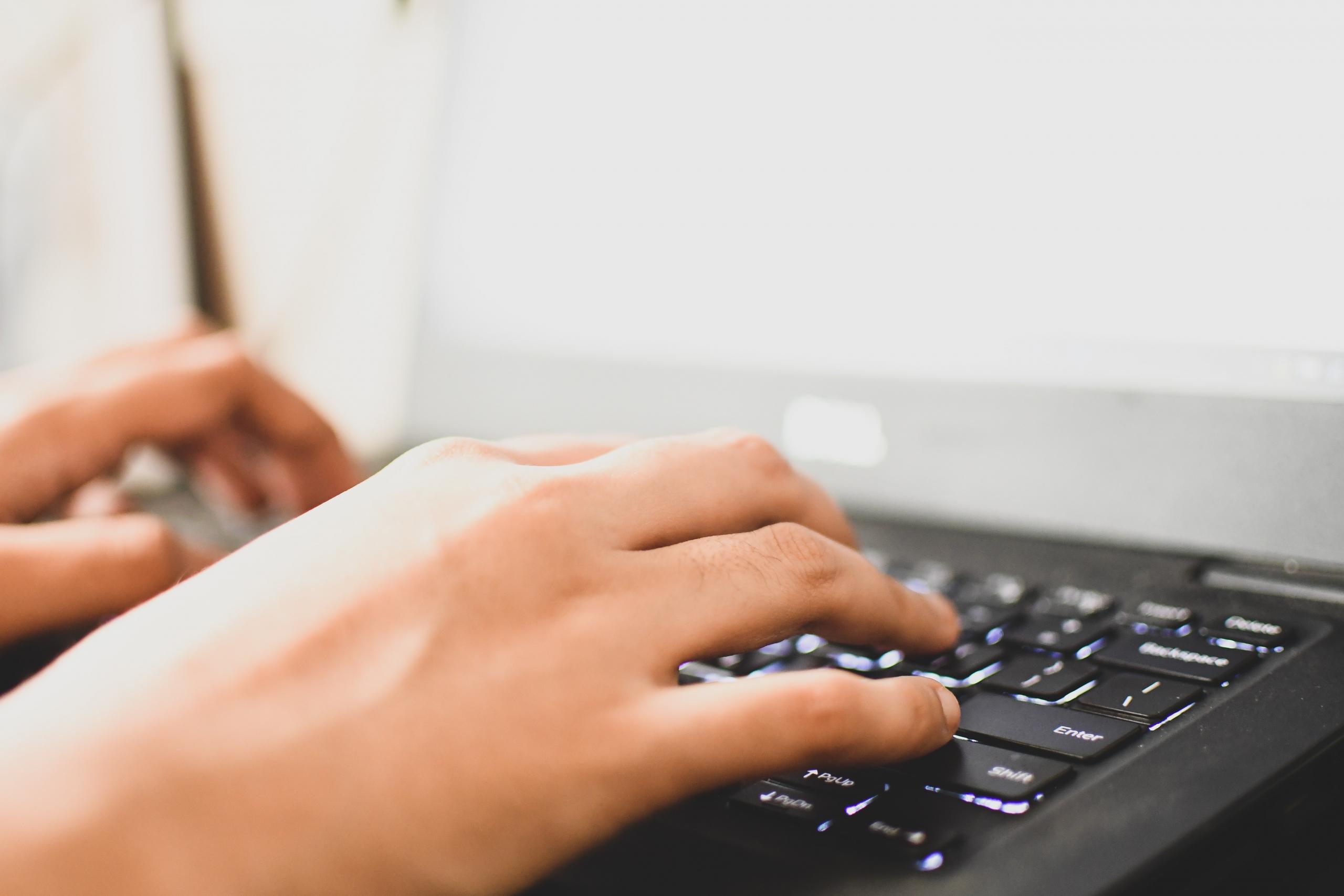 close up of person's hands on computer keyboard