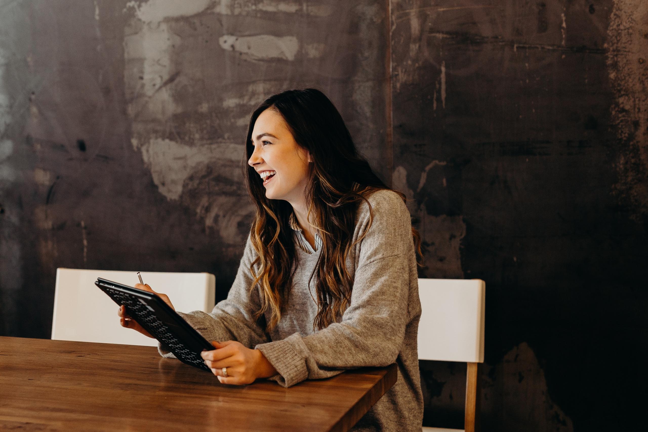 person holding electronic tablet and sitting at boardroom table