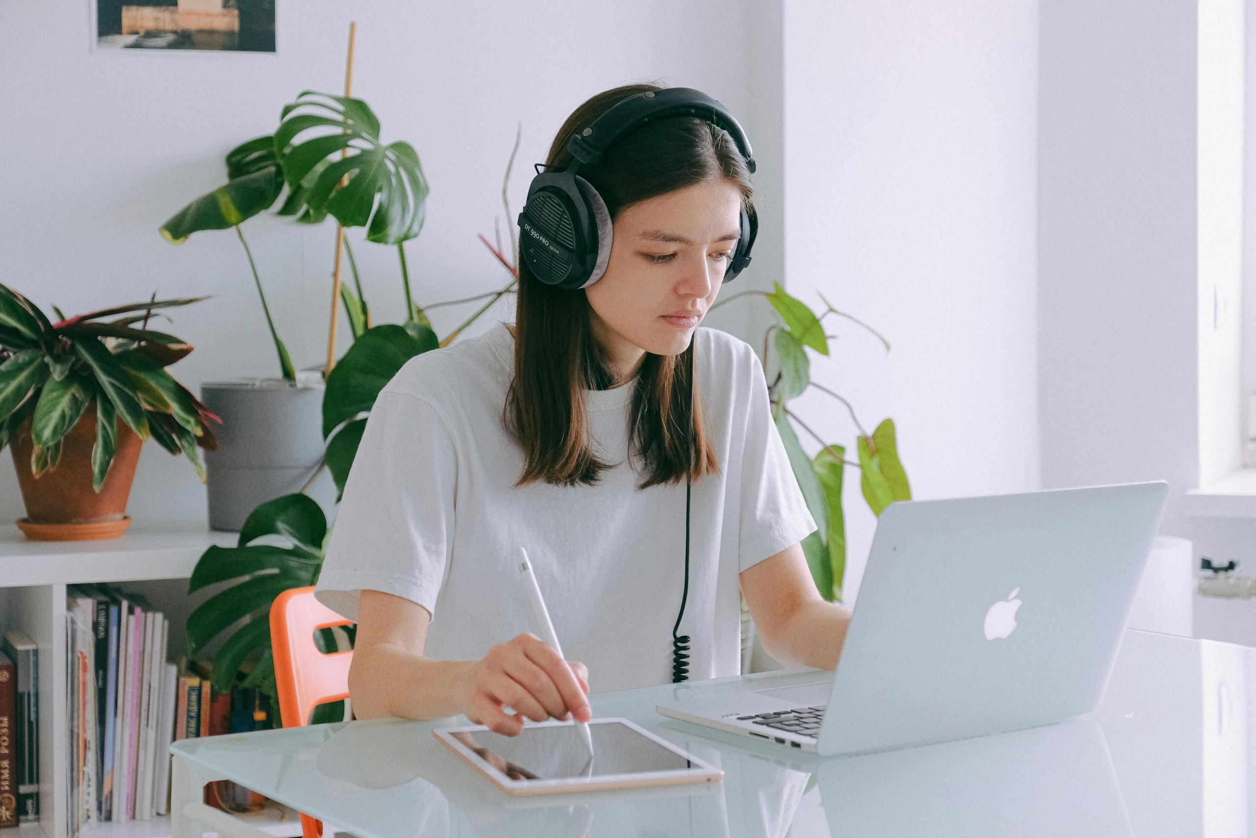 student wearing headphones using laptop and drawing software on tablet