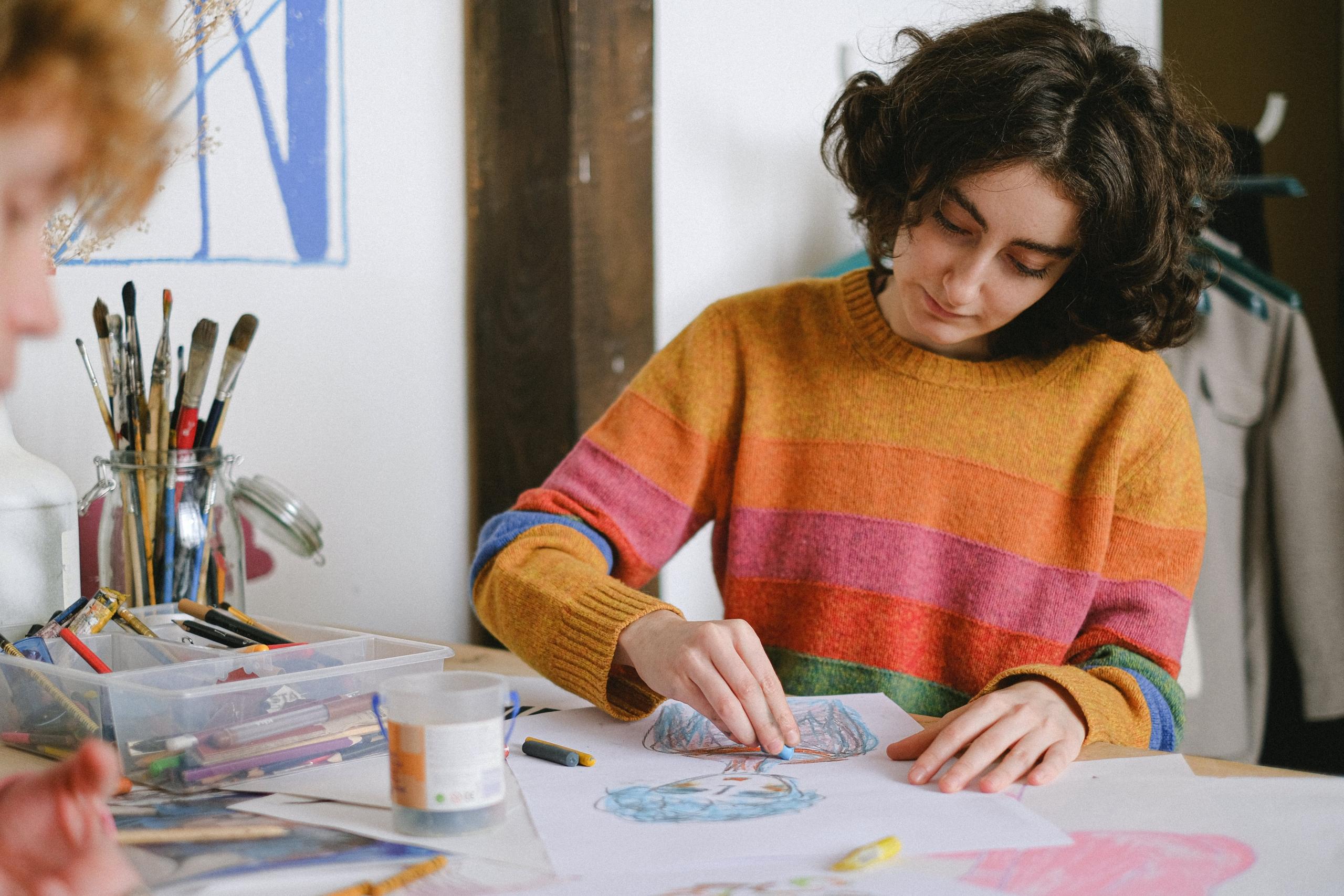 girl and boy making crayon drawings of people in art room