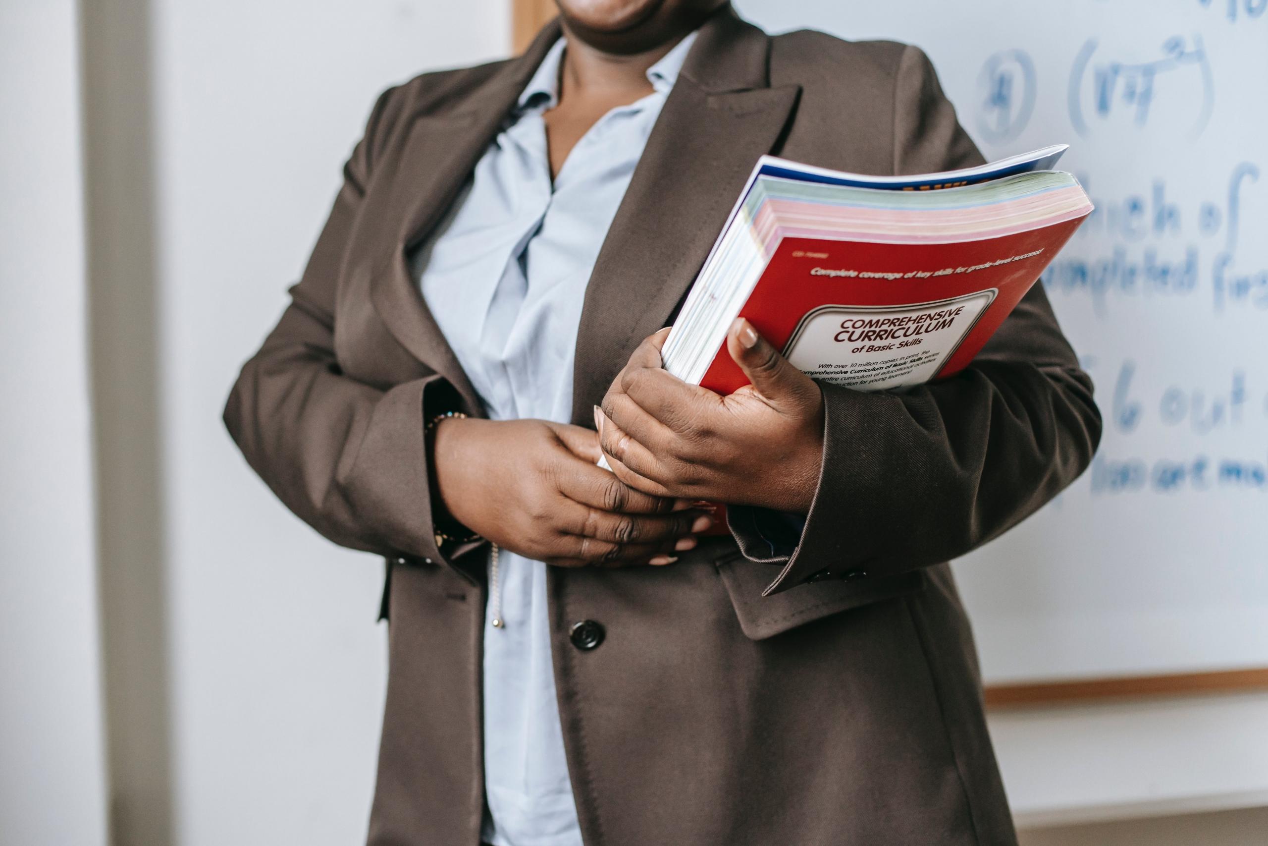 tutor preparing for lesson carrying a stack of books on the curriculum