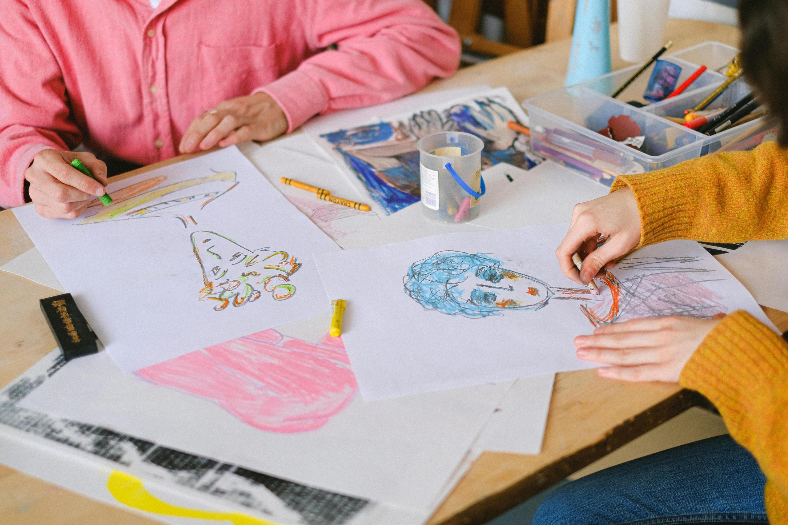 students learning how to draw people using coloured pencils and crayons