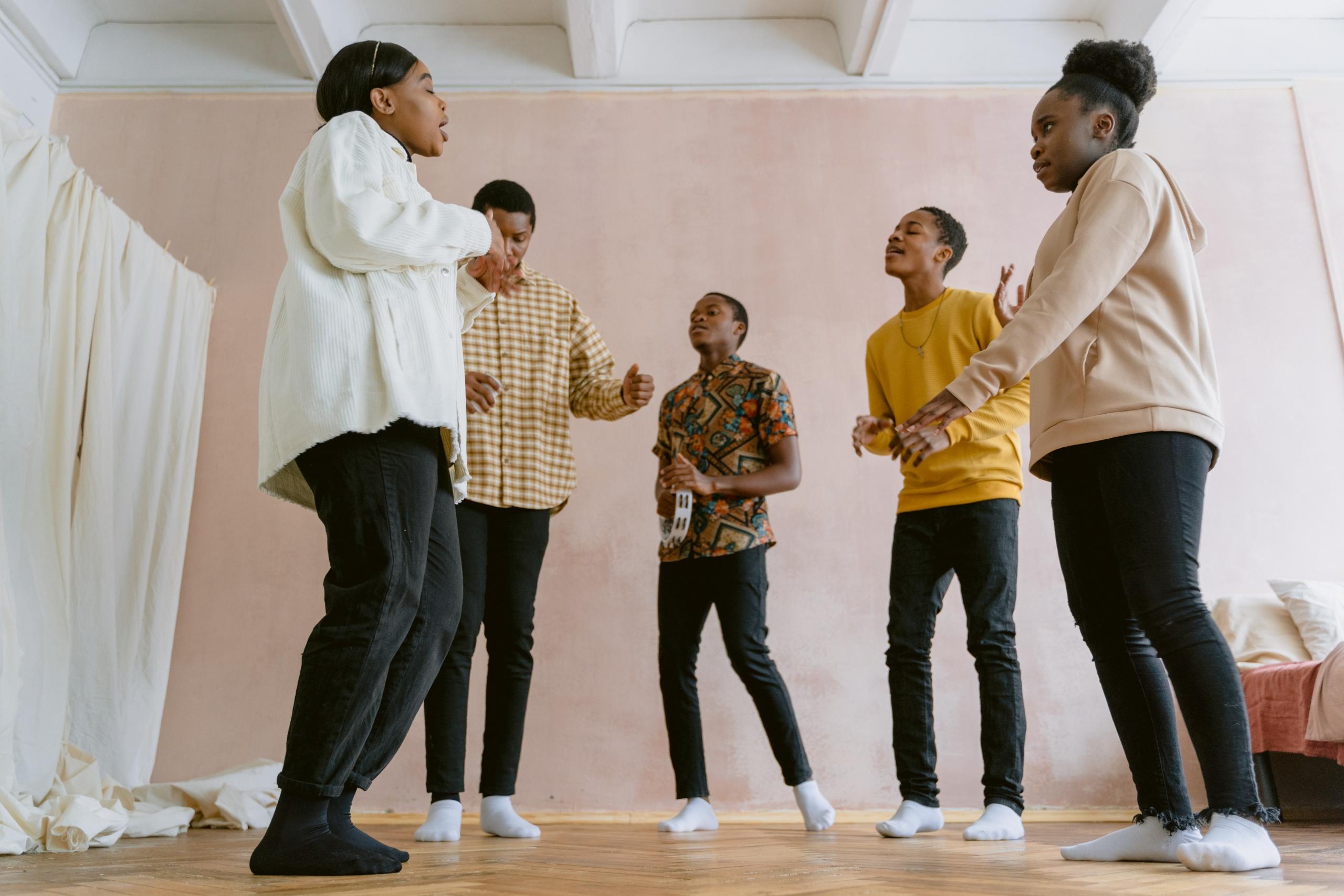 group of singers standing in a circle singing while someone plays the tambourine