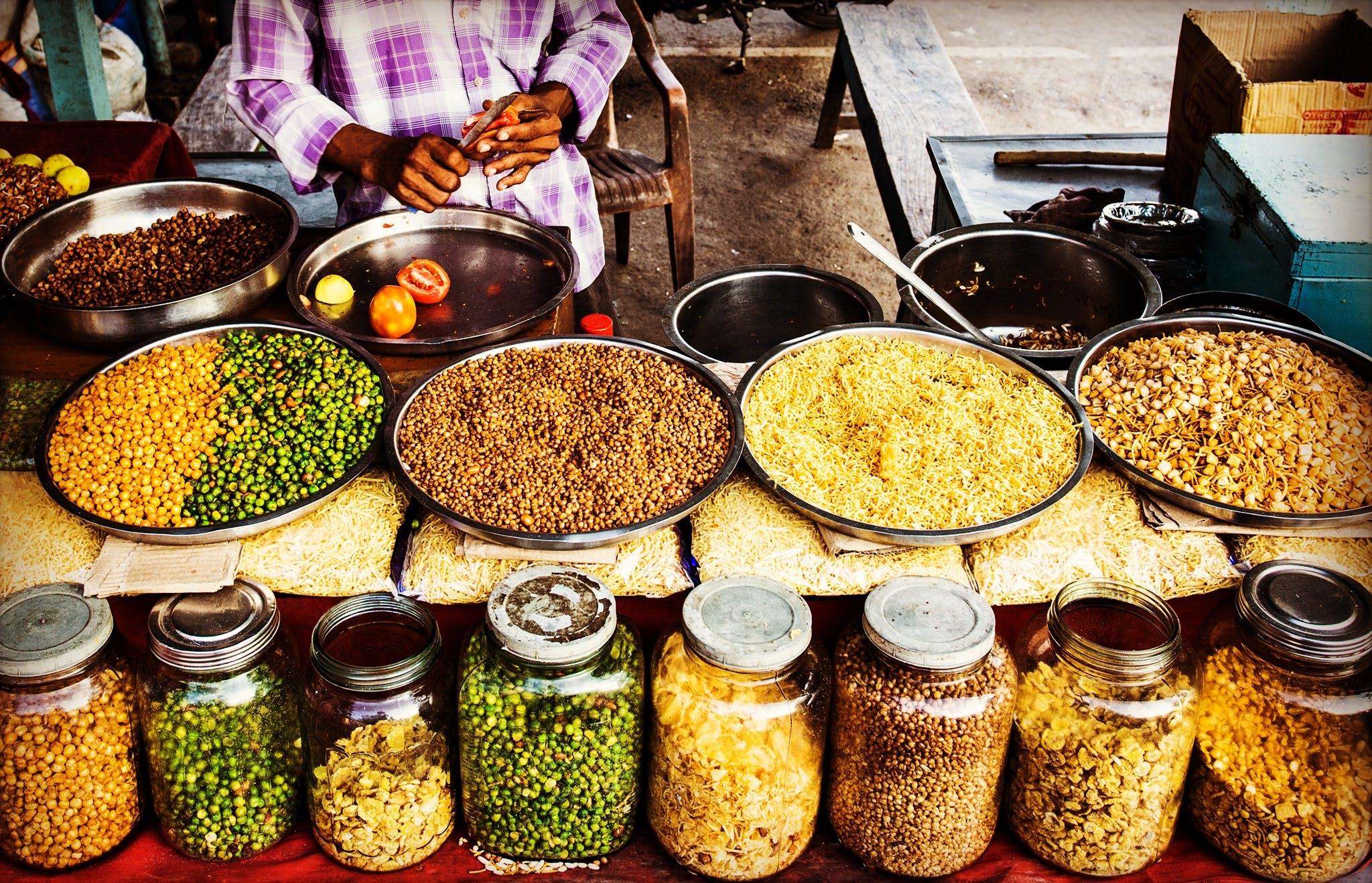 assorted grains on display in jars and large dishes in marketplace in India