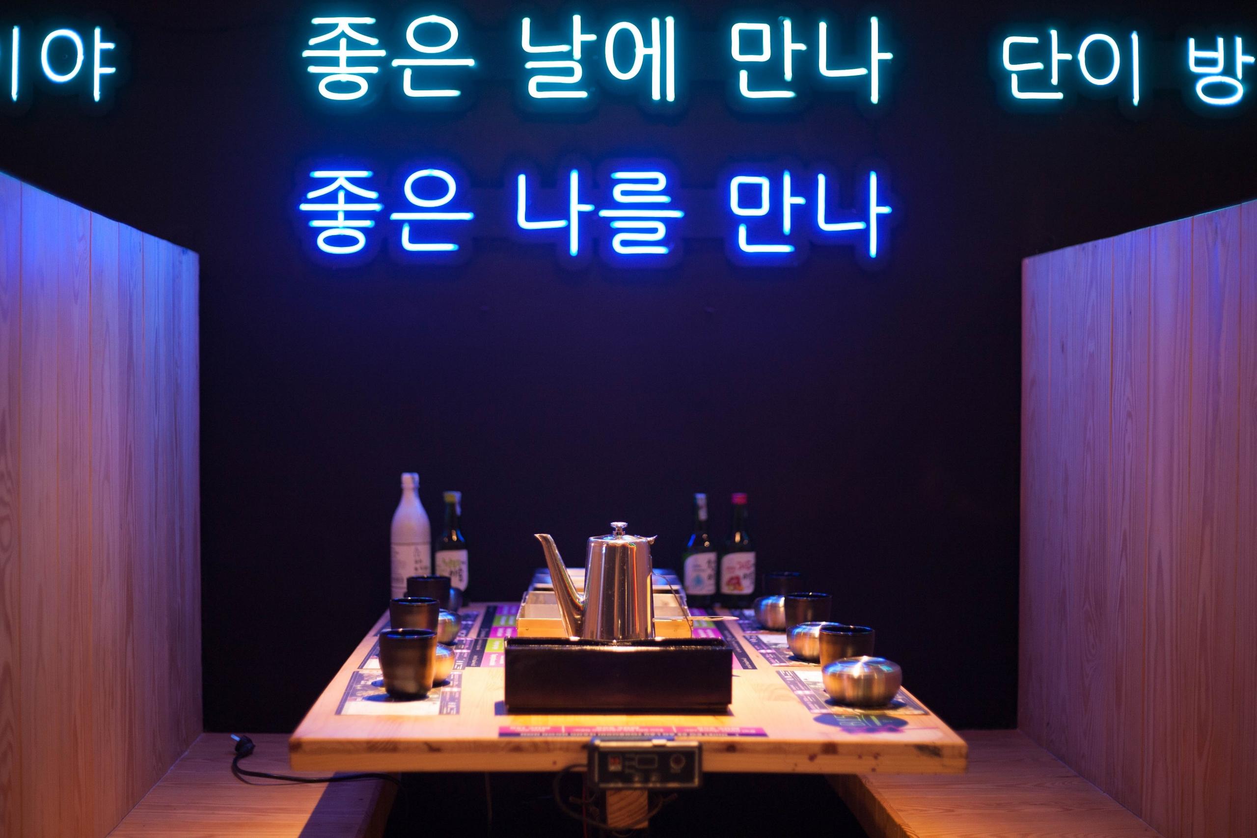 restaurant with dark walls and Korean writing in neon