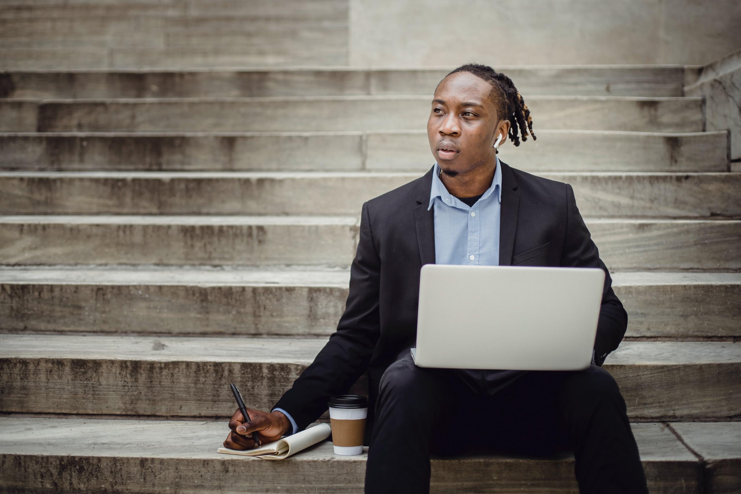 man sitting on stairs using laptop