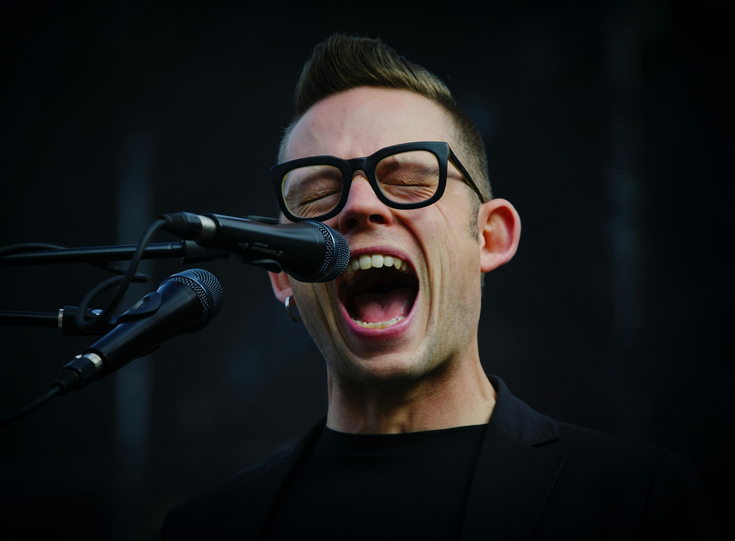 man screaming singing into microphone on stage