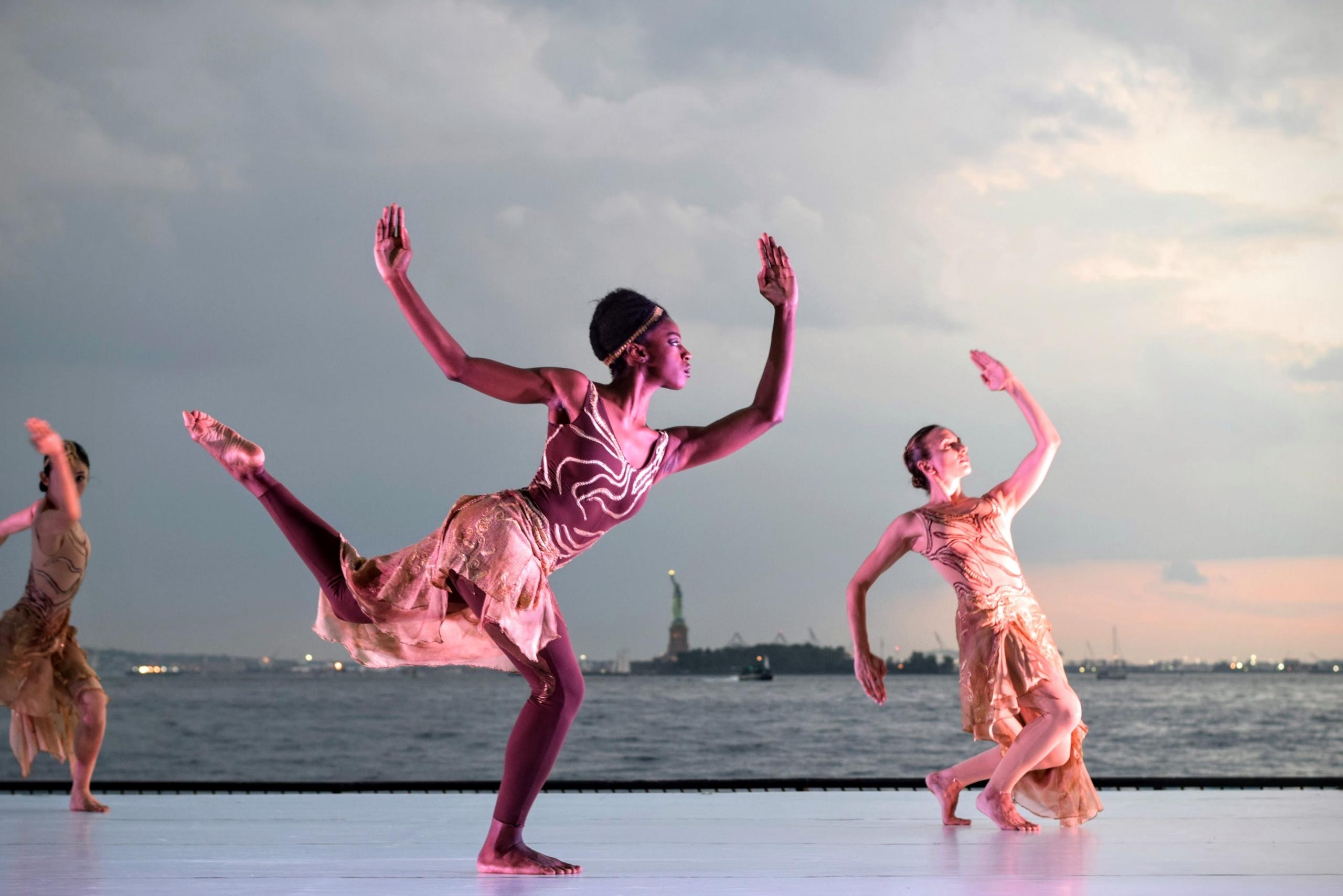 three women dancing near body of water