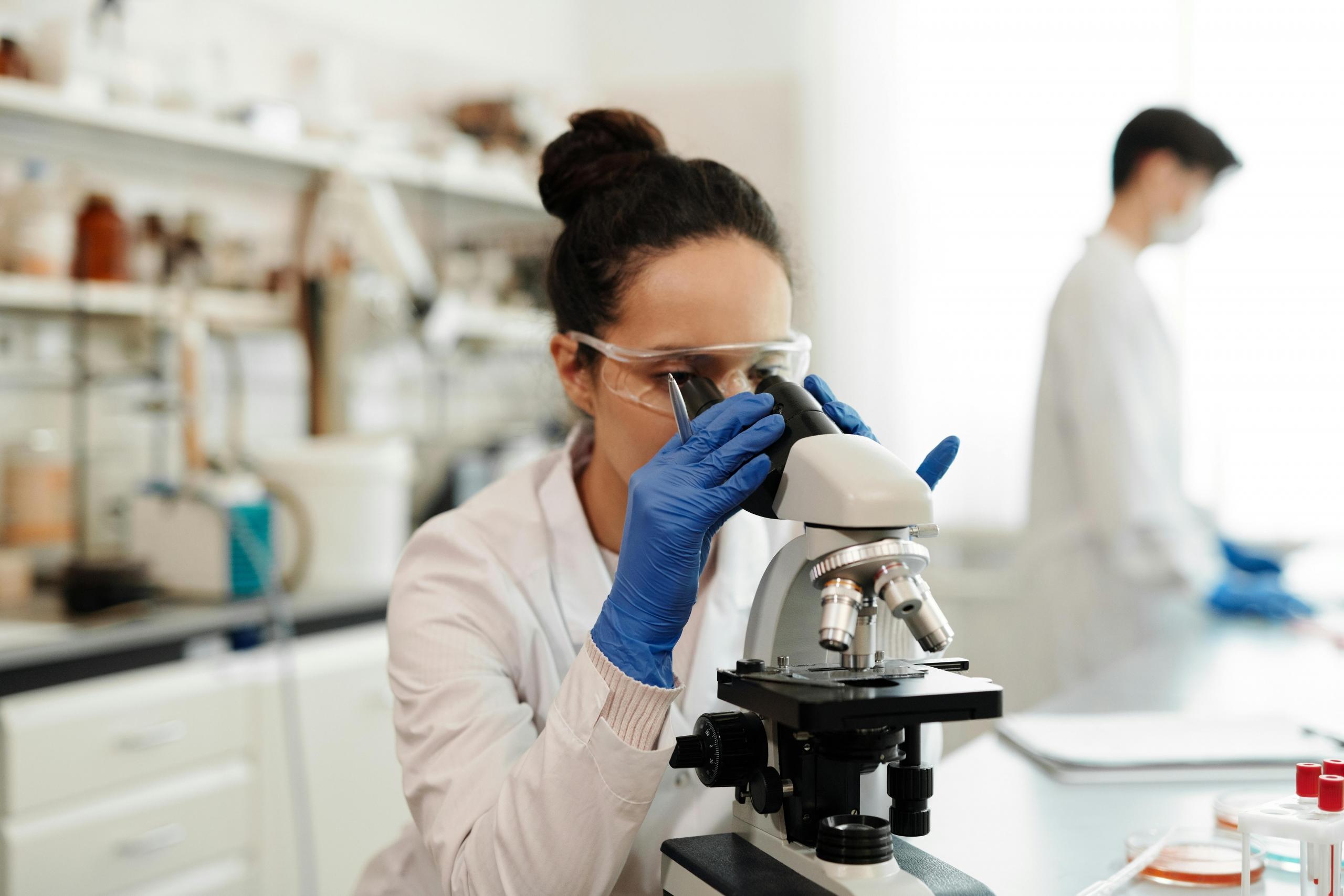 lab technician viewing samples through a microscope