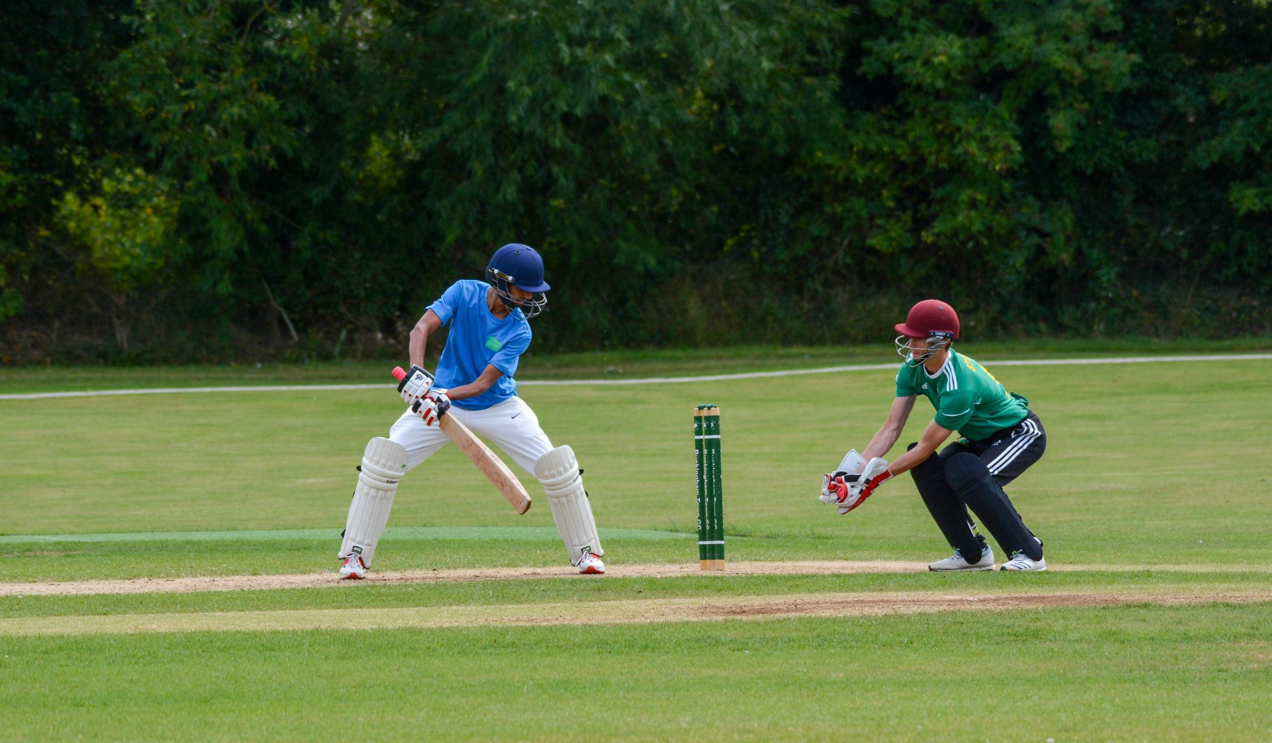 wicket keeper catching ball on cricket pitch