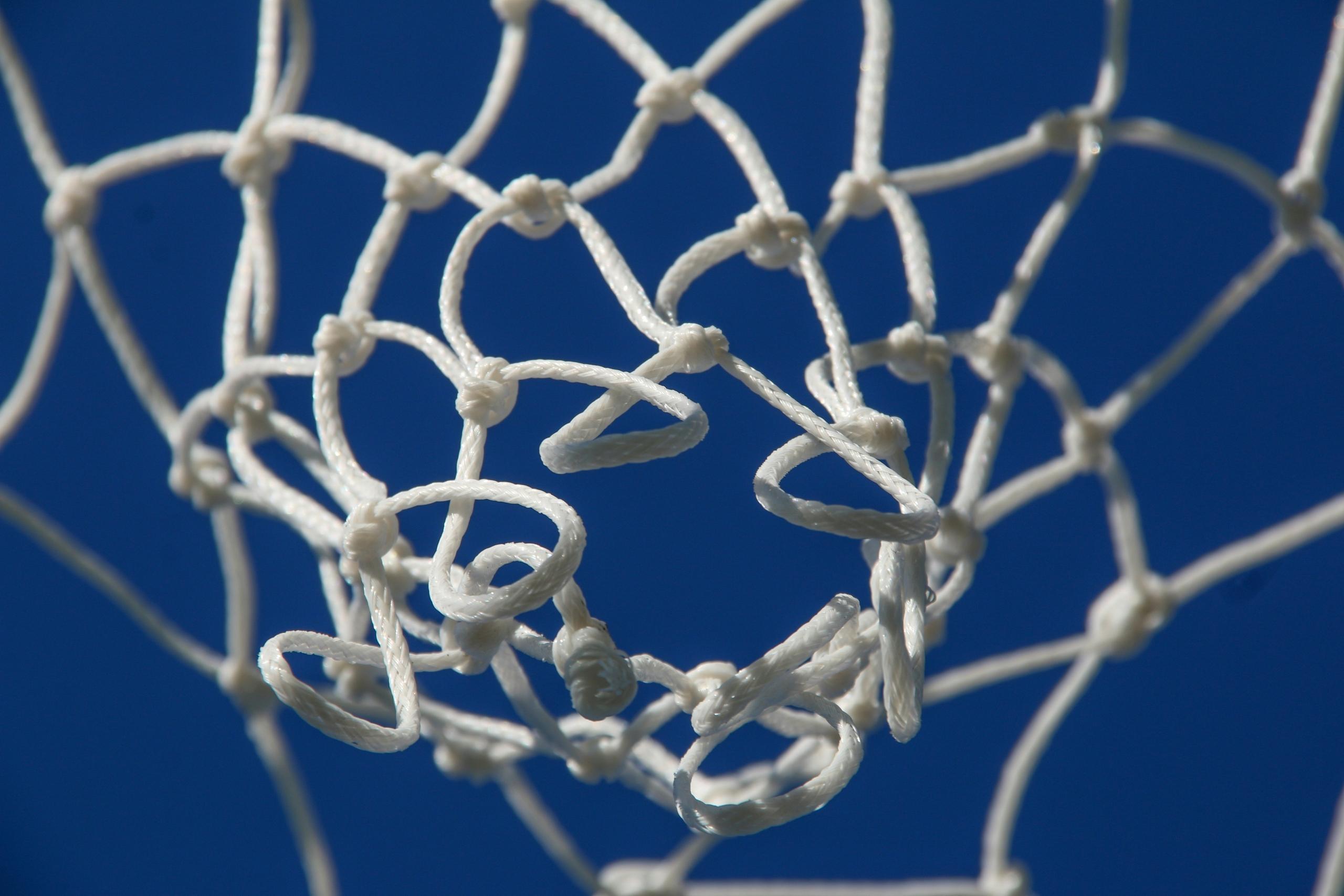 shot of white netball net from below looking up to clear blue skies