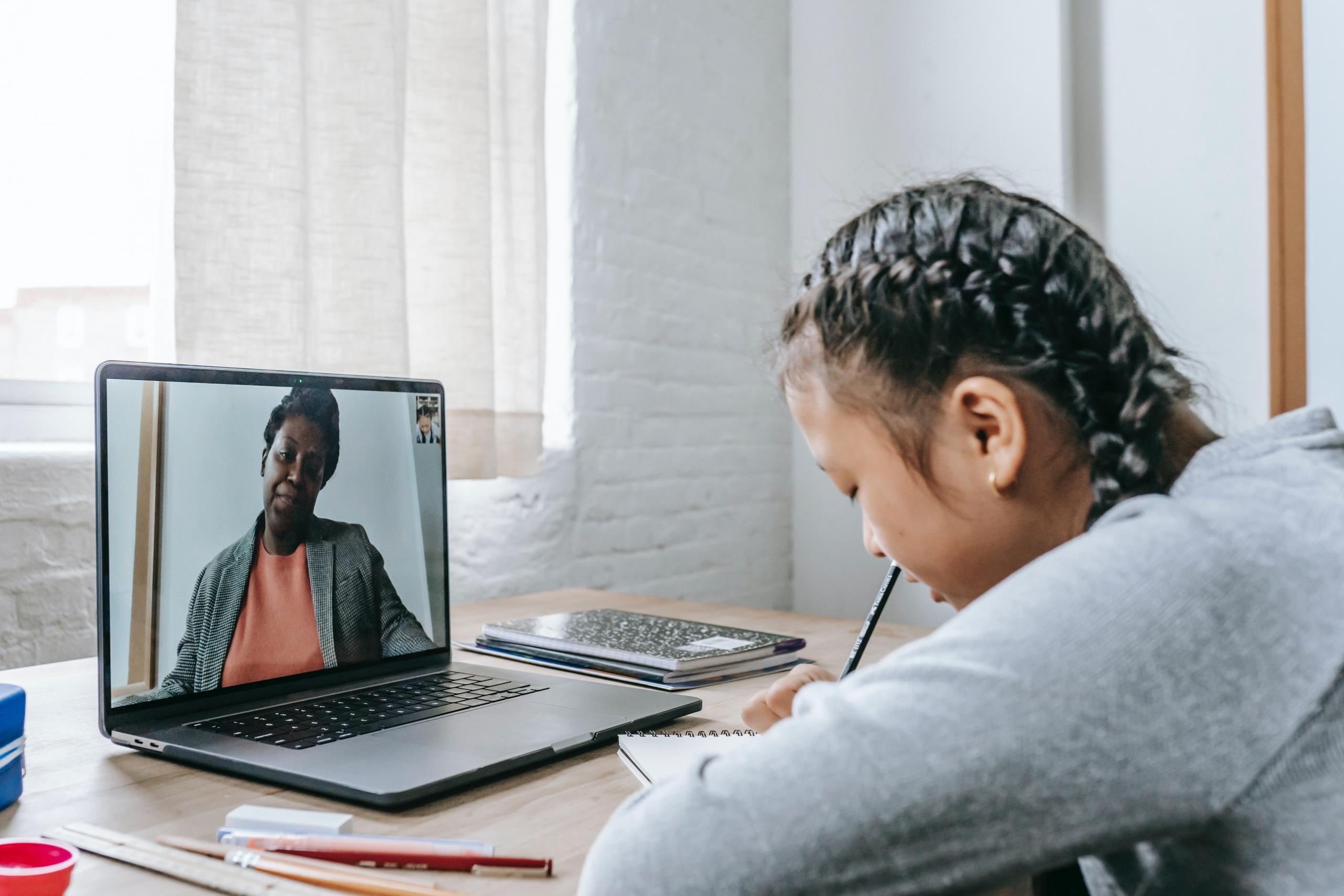 child making notes during online lesson with private tutor