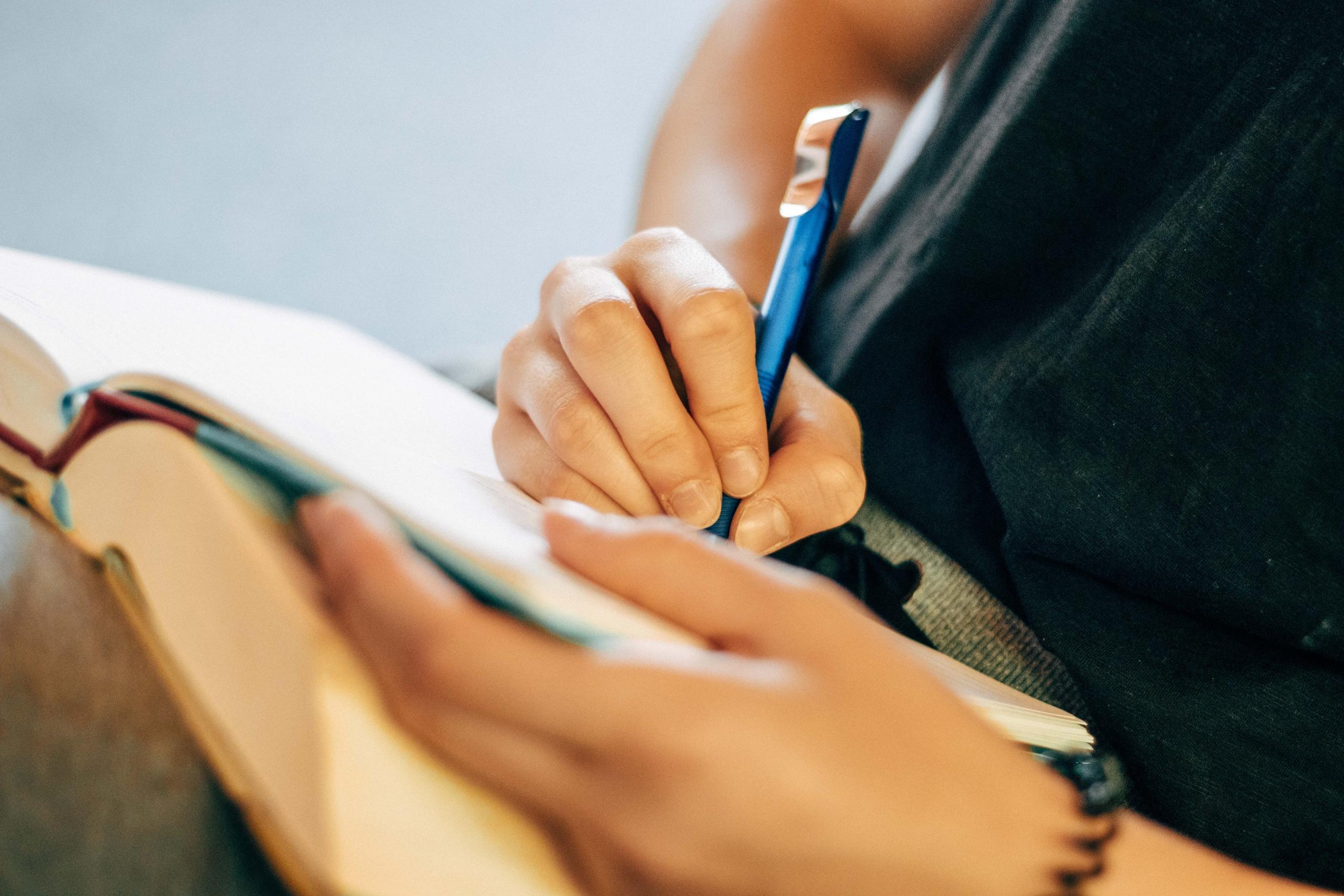 student writing with pen in book