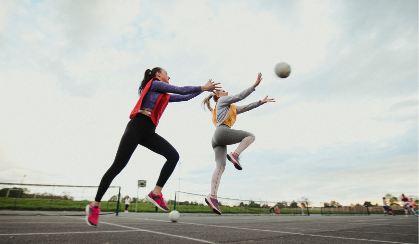 Two Netball Players on opposing teams jumping to intercept ball