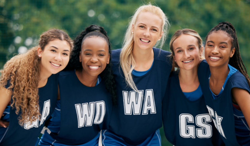 members of netball team wearing navy blue uniforms with their positions emblazoned in white on the front