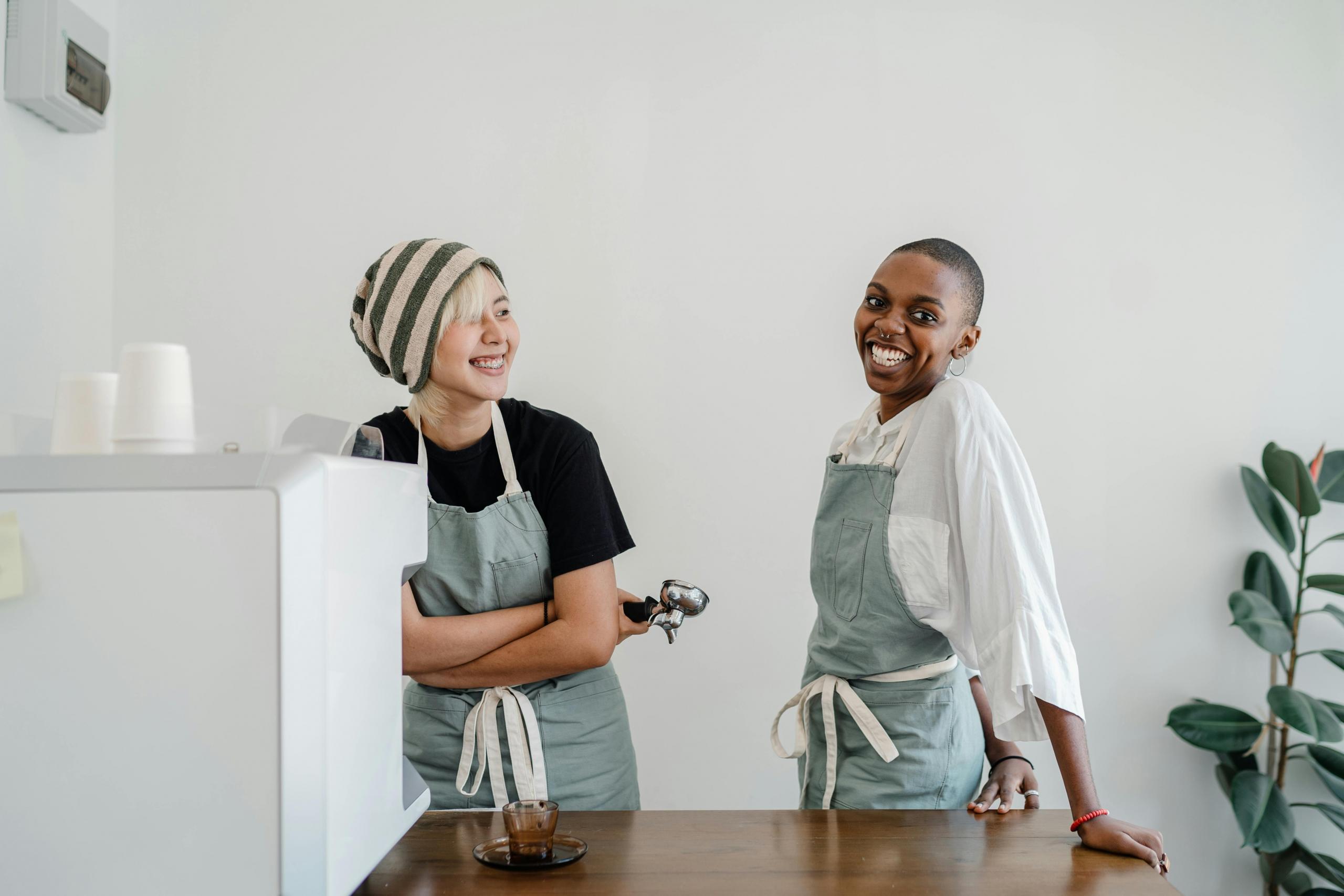 two happy colleagues standing behind counter in coffee shop