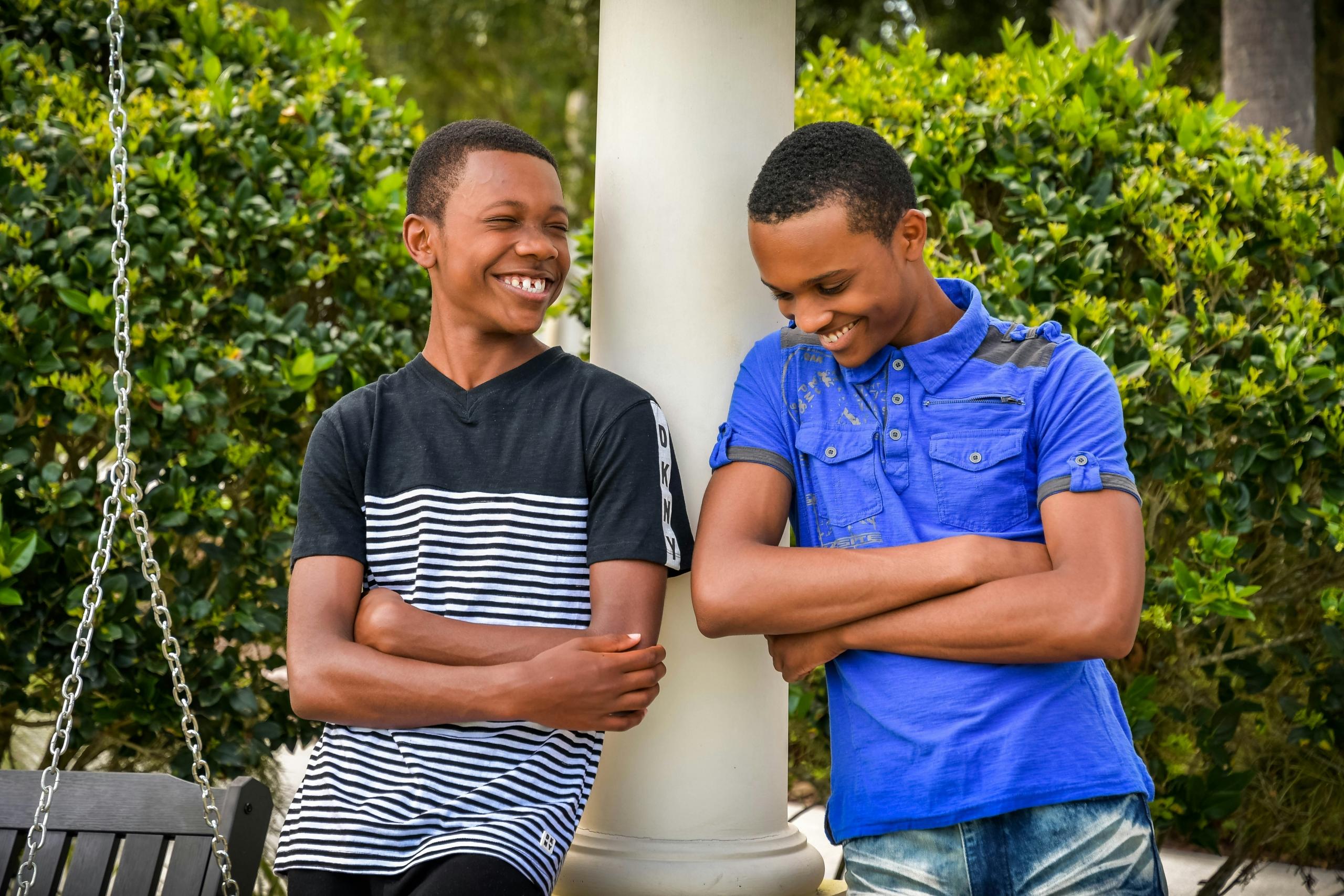 two happy teenage boys leaning against a pillar