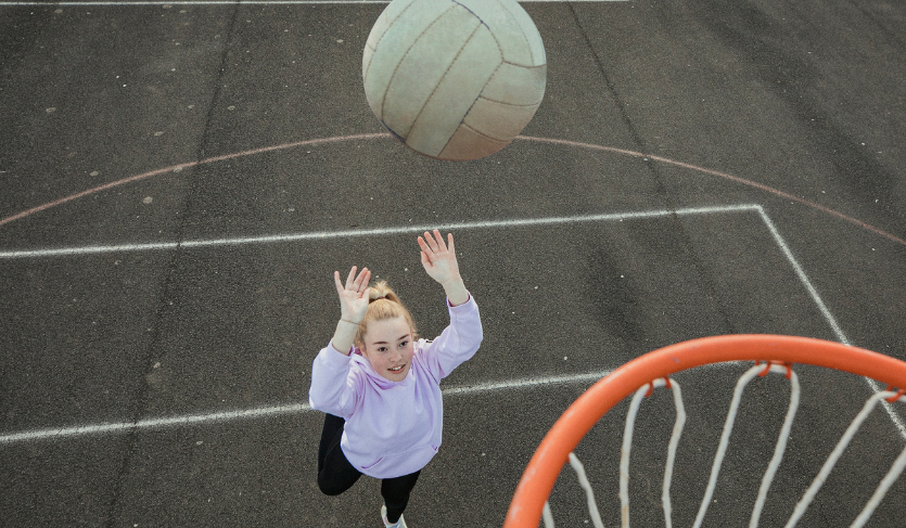 child about to shoot netball into hoop