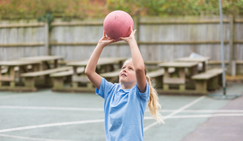school learner about to shoot netball into hoop