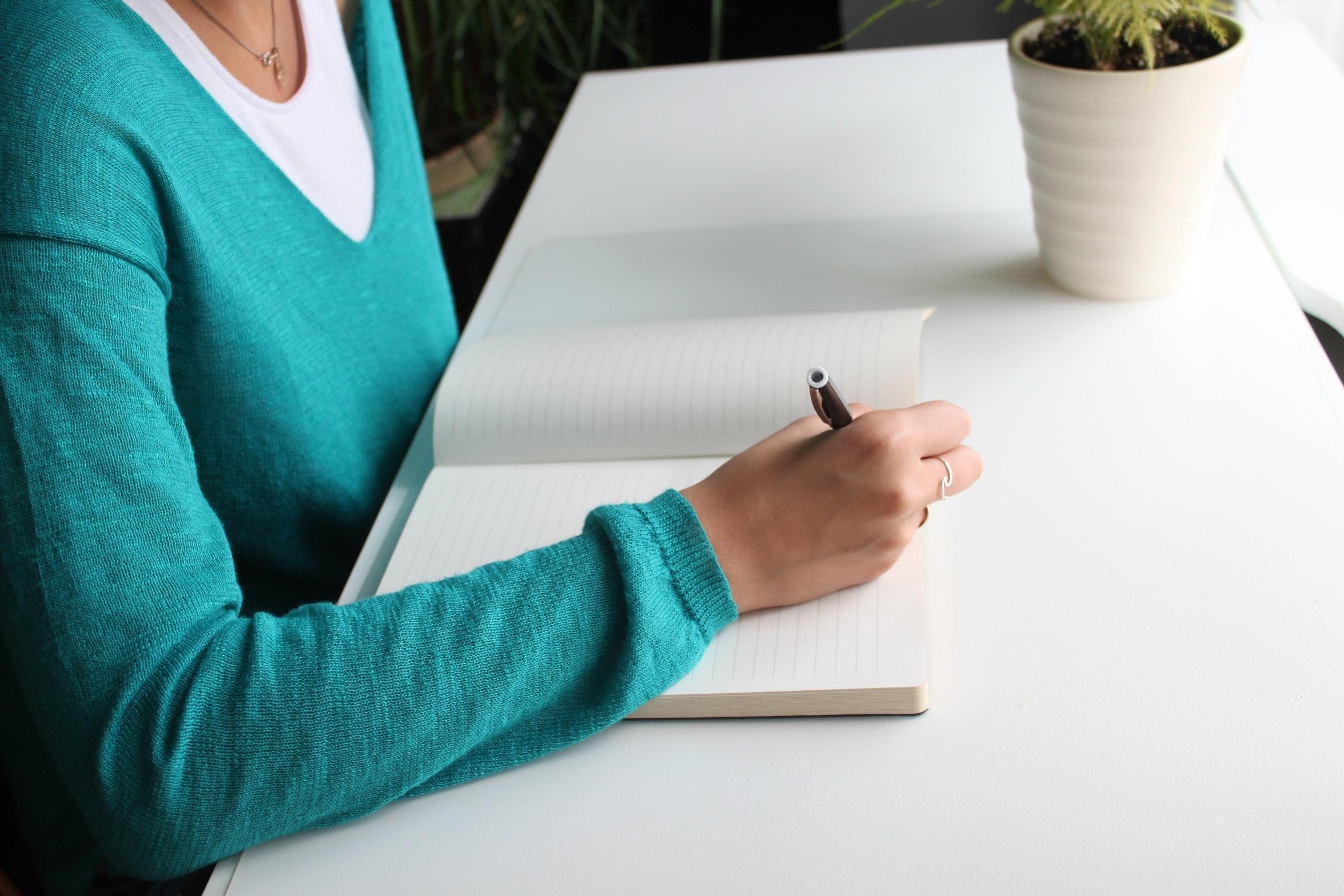 woman sitting at desk making handwritten notes