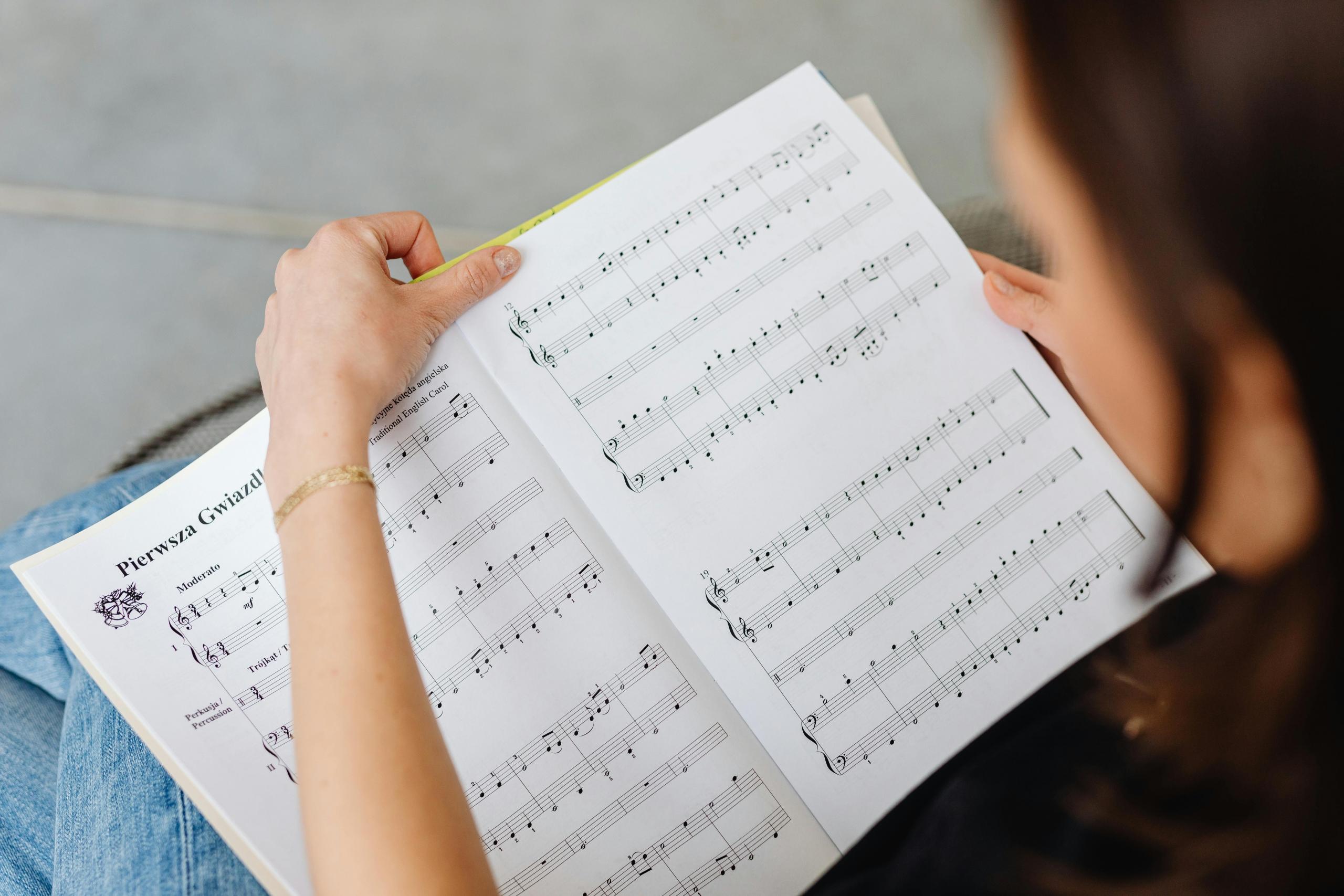 woman sitting down with open book of sheet music placed on her lap
