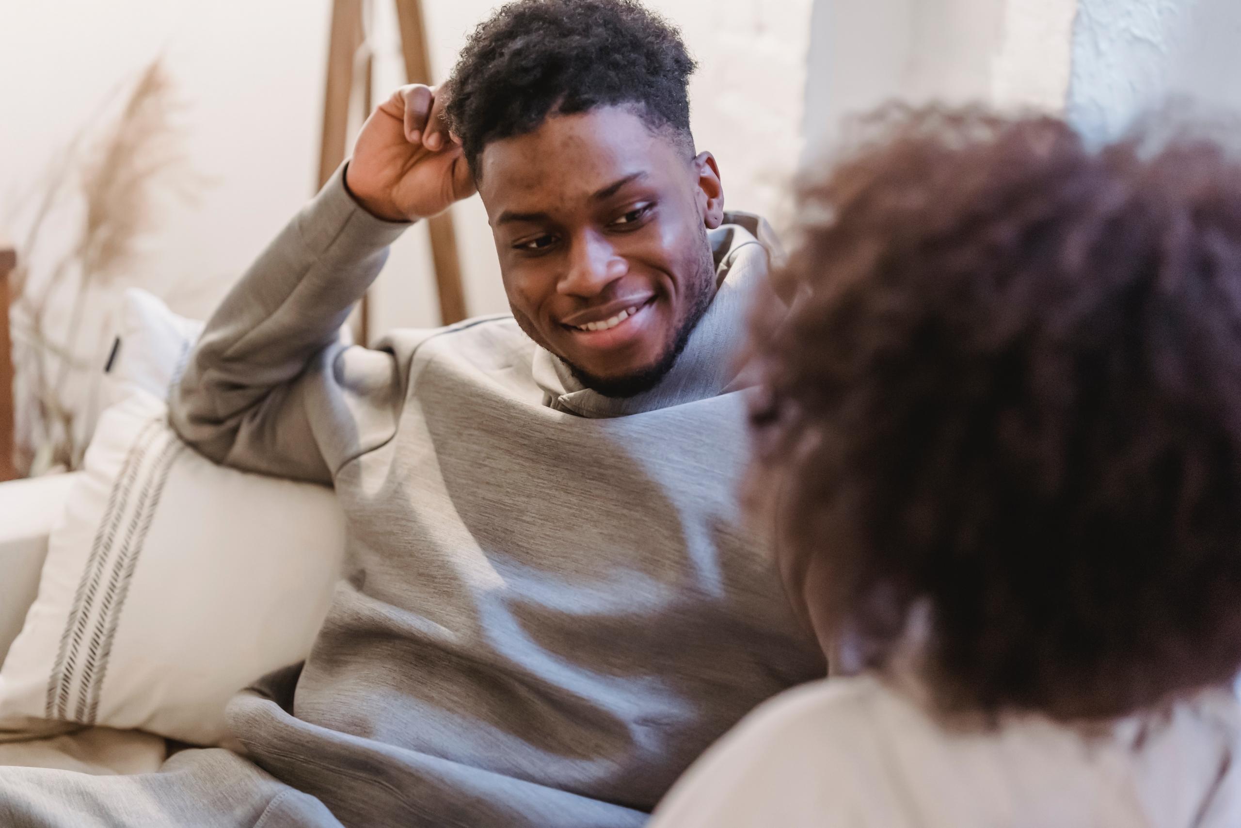 man sitting on couch smiling at woman
