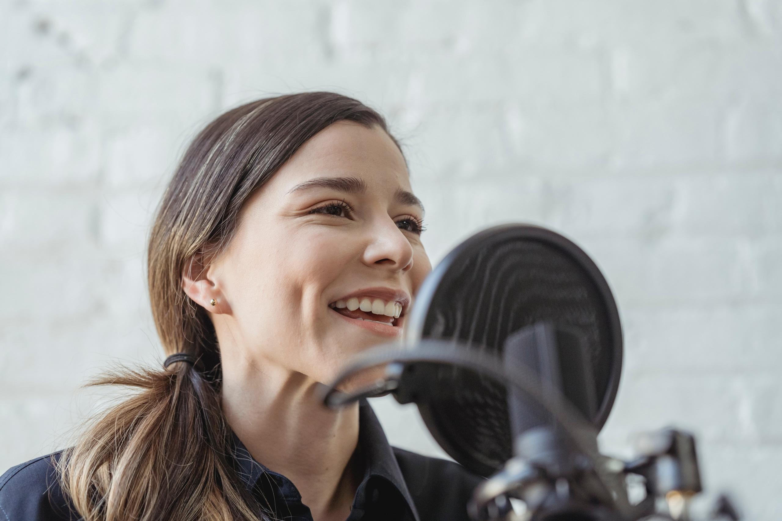 singer in recording studio standing behind microphone