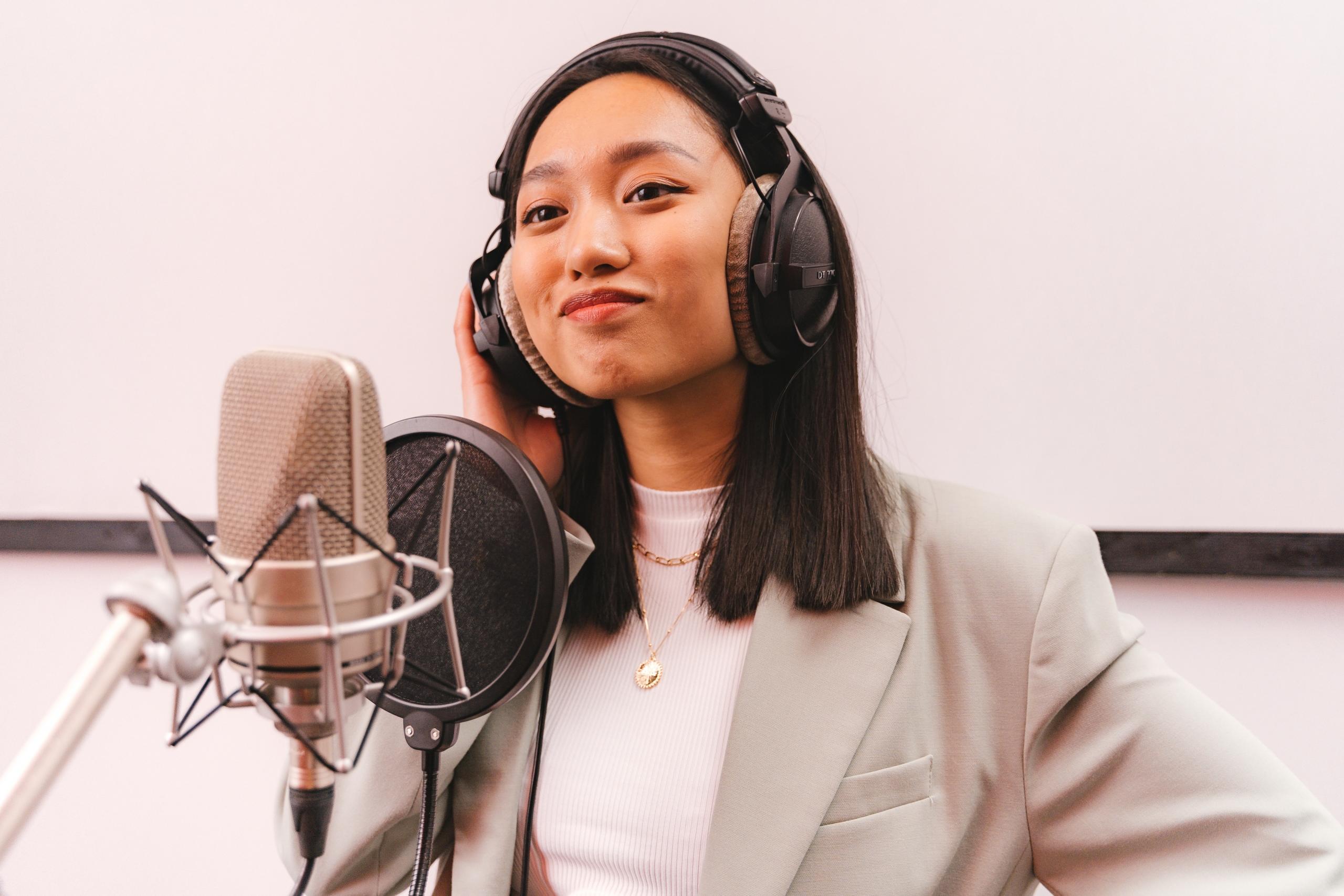 singer in recording studio wearing headphones and standing behind microphone