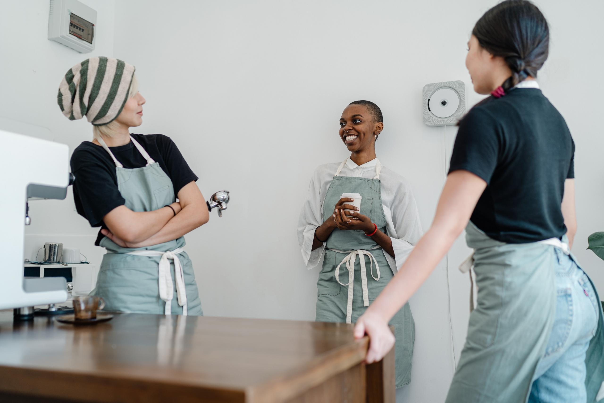 three friends wearing aprons standing around chatting
