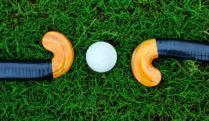 hockey ball placed between two hockey sticks on astroturf