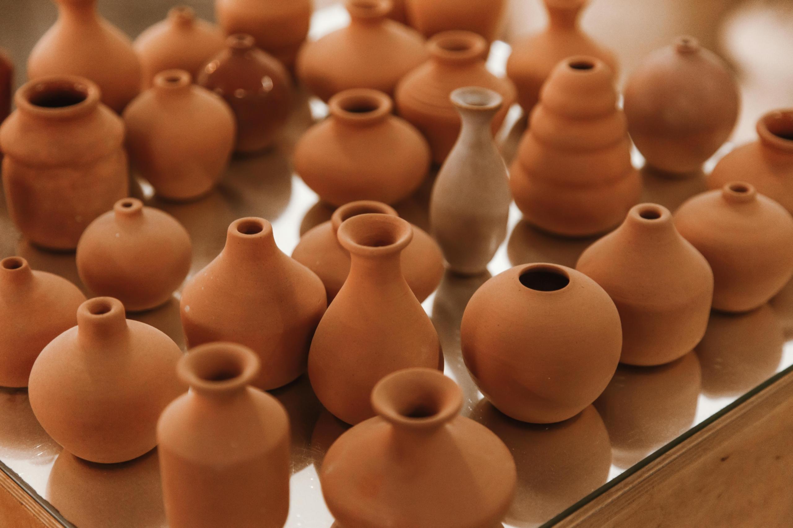 an assortment of different shaped clay pots and vases on display