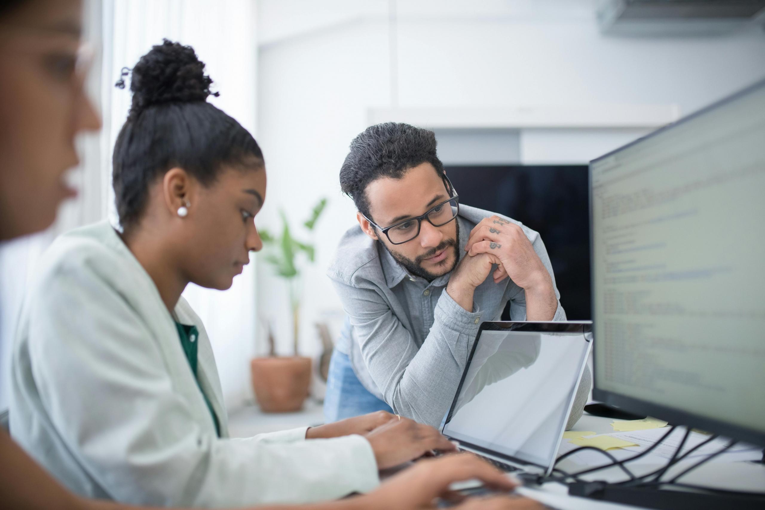 group of people in office, with supervisor looking at their progress on computer screens
