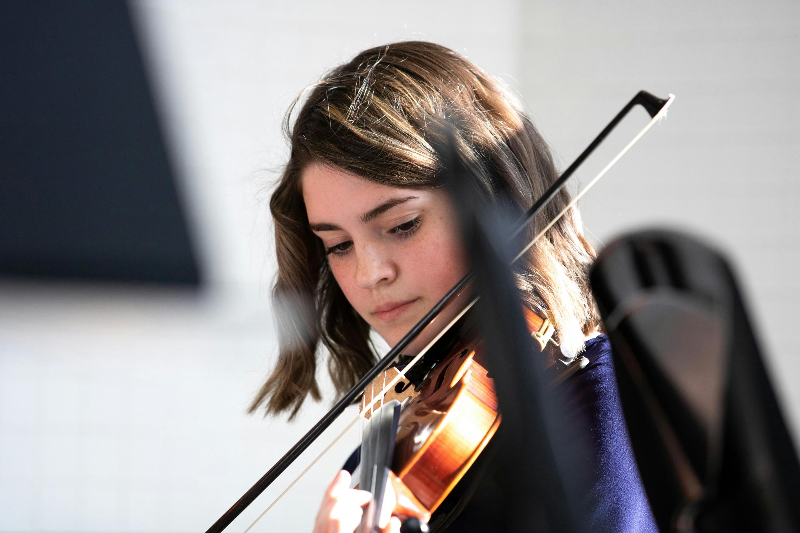 young violinist in orchestra holding bow in her hand