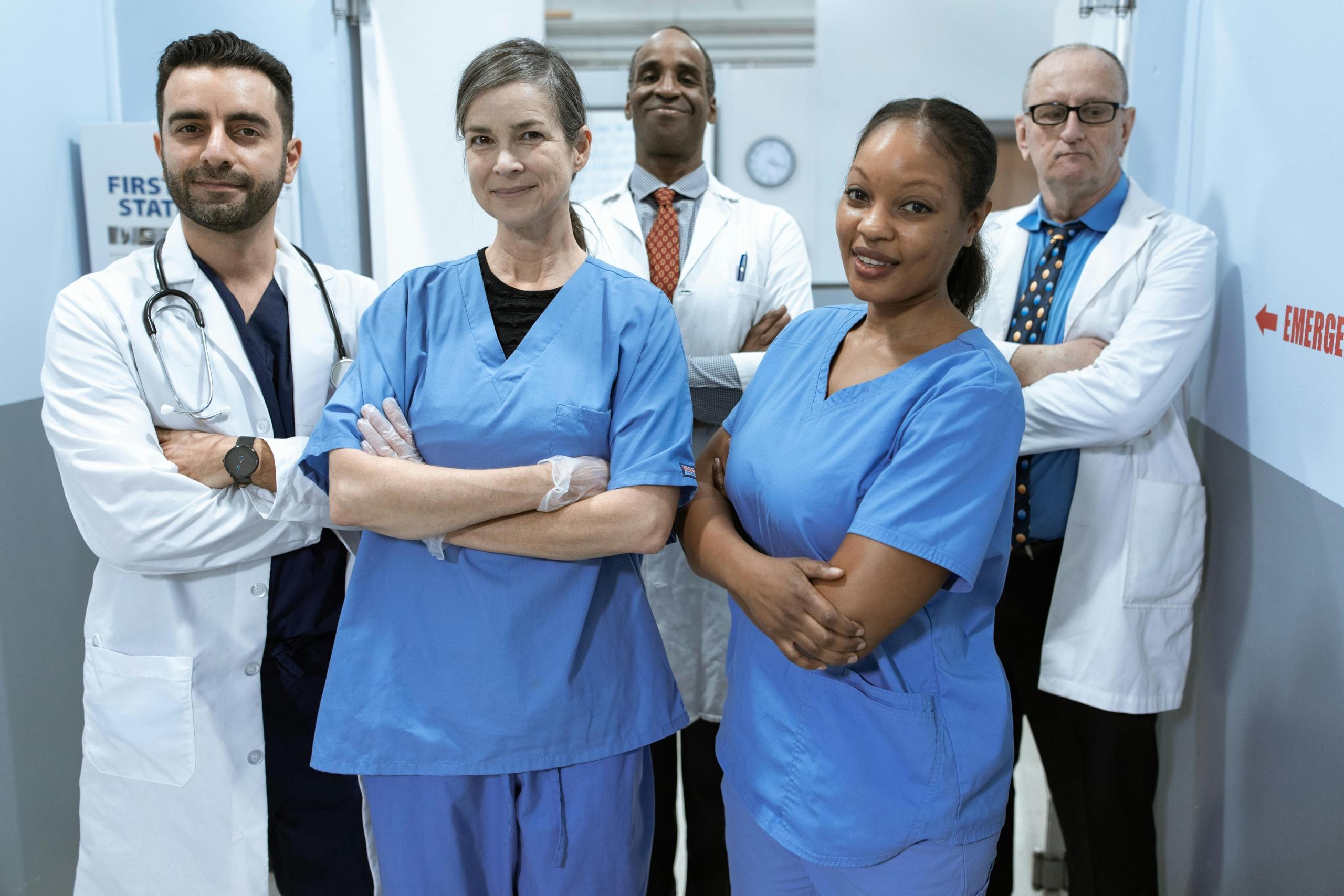 two nurses standing with three doctors in hospital corridor