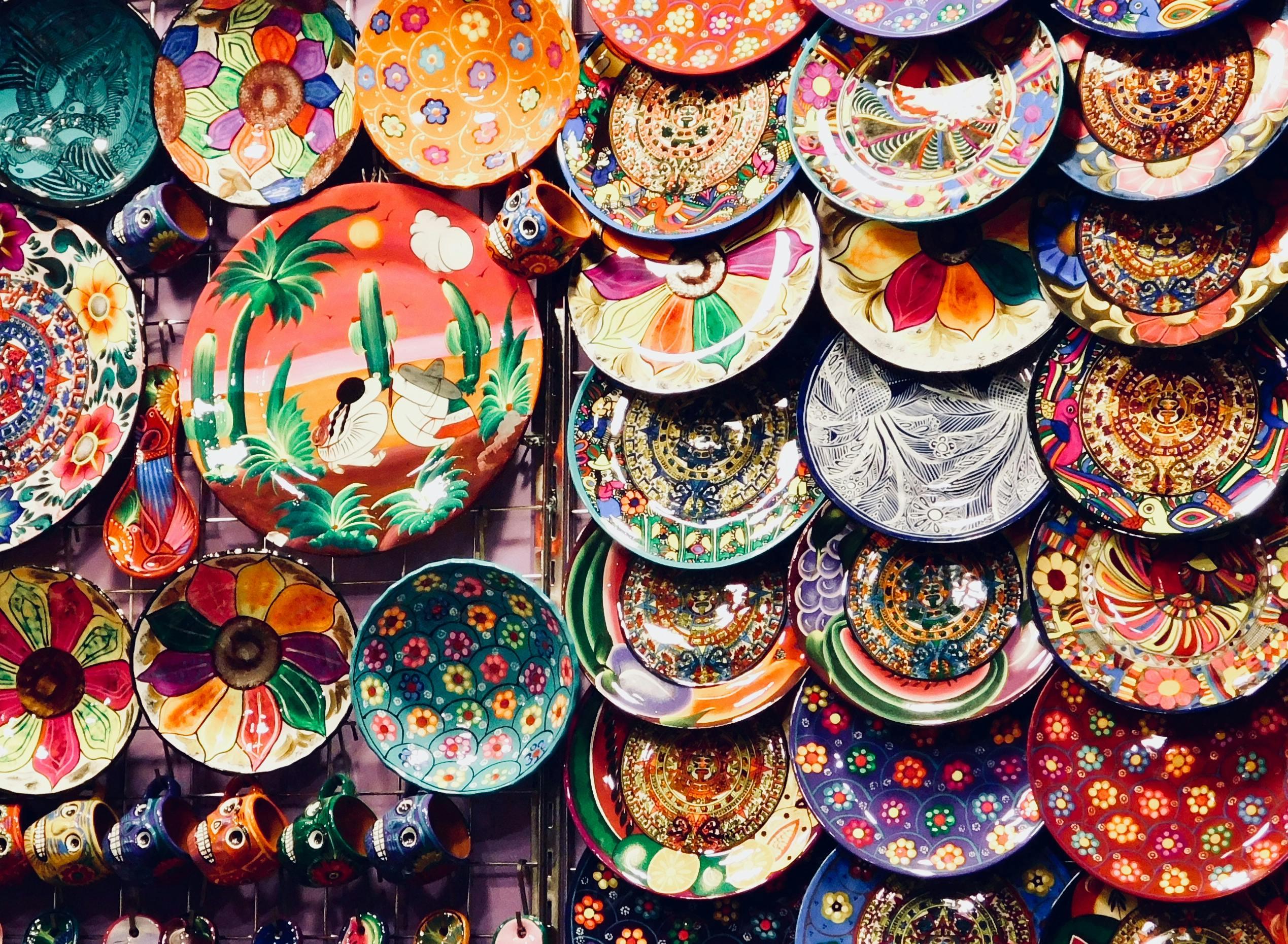 an assortment of brightly painted ceramics hanging on display in a market
