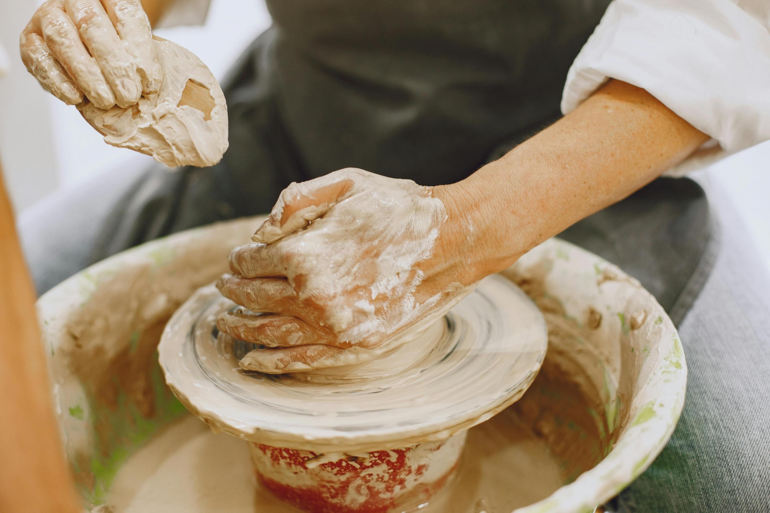 person using a pottery wheel to shape clay