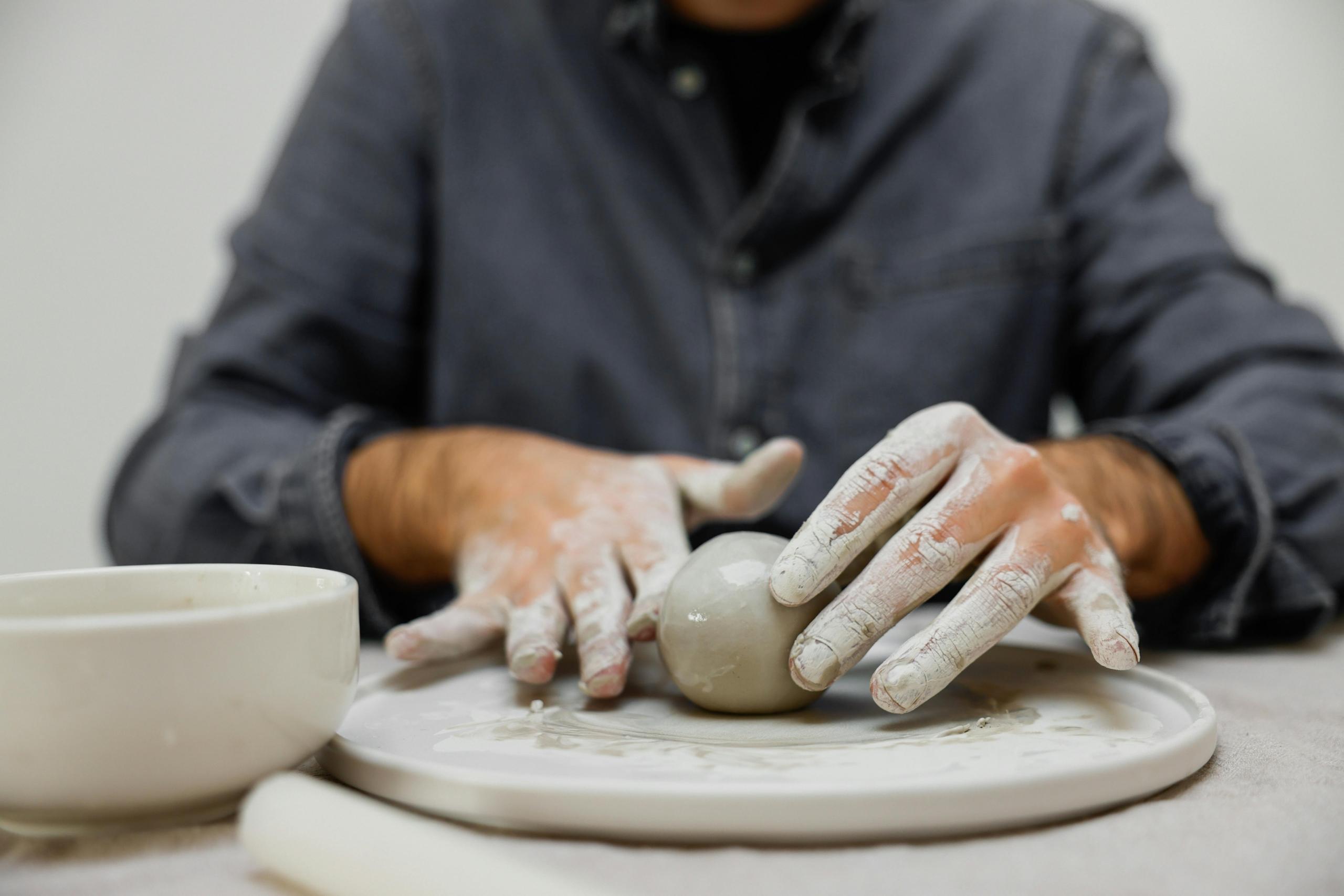 person moulding clay ball with their hands