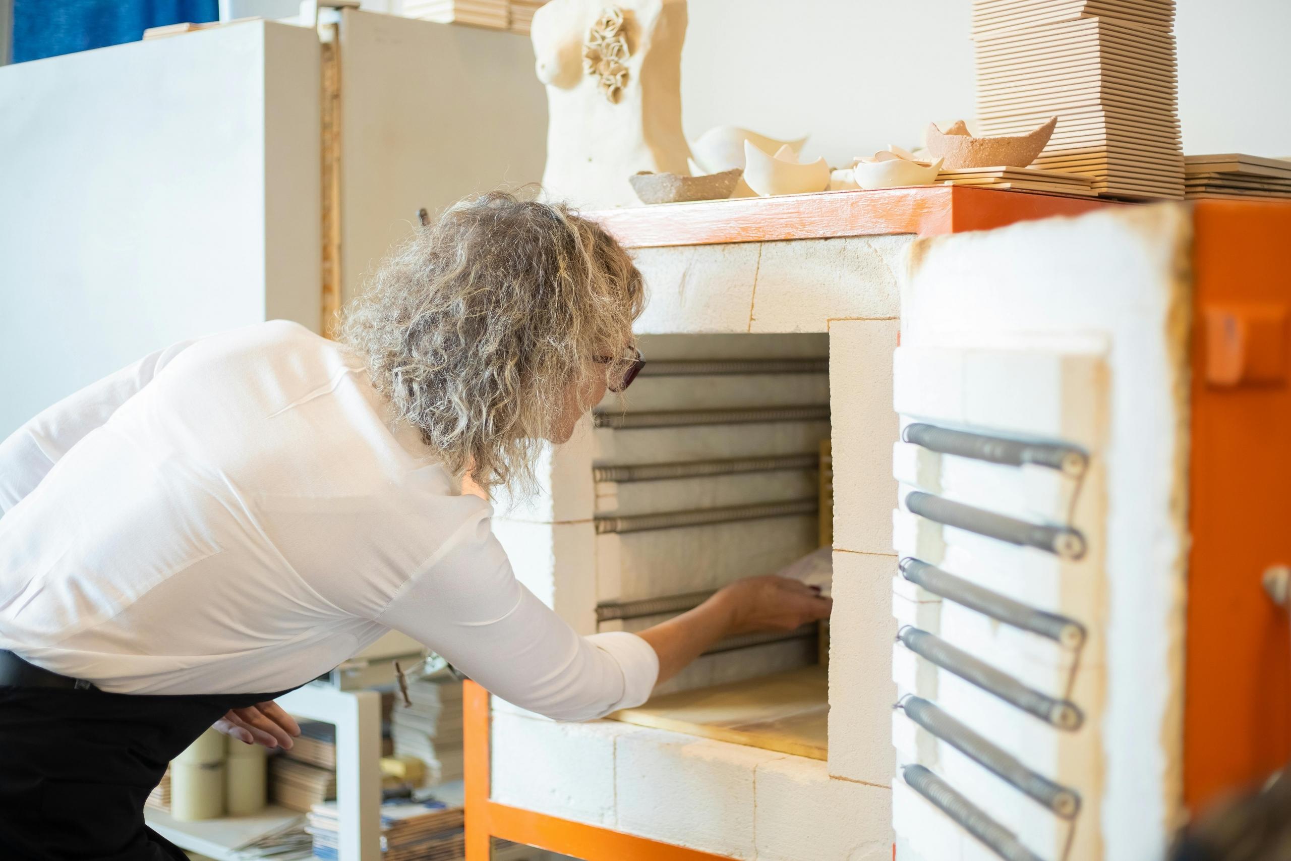 woman placing ceramic creations in a pottery kiln