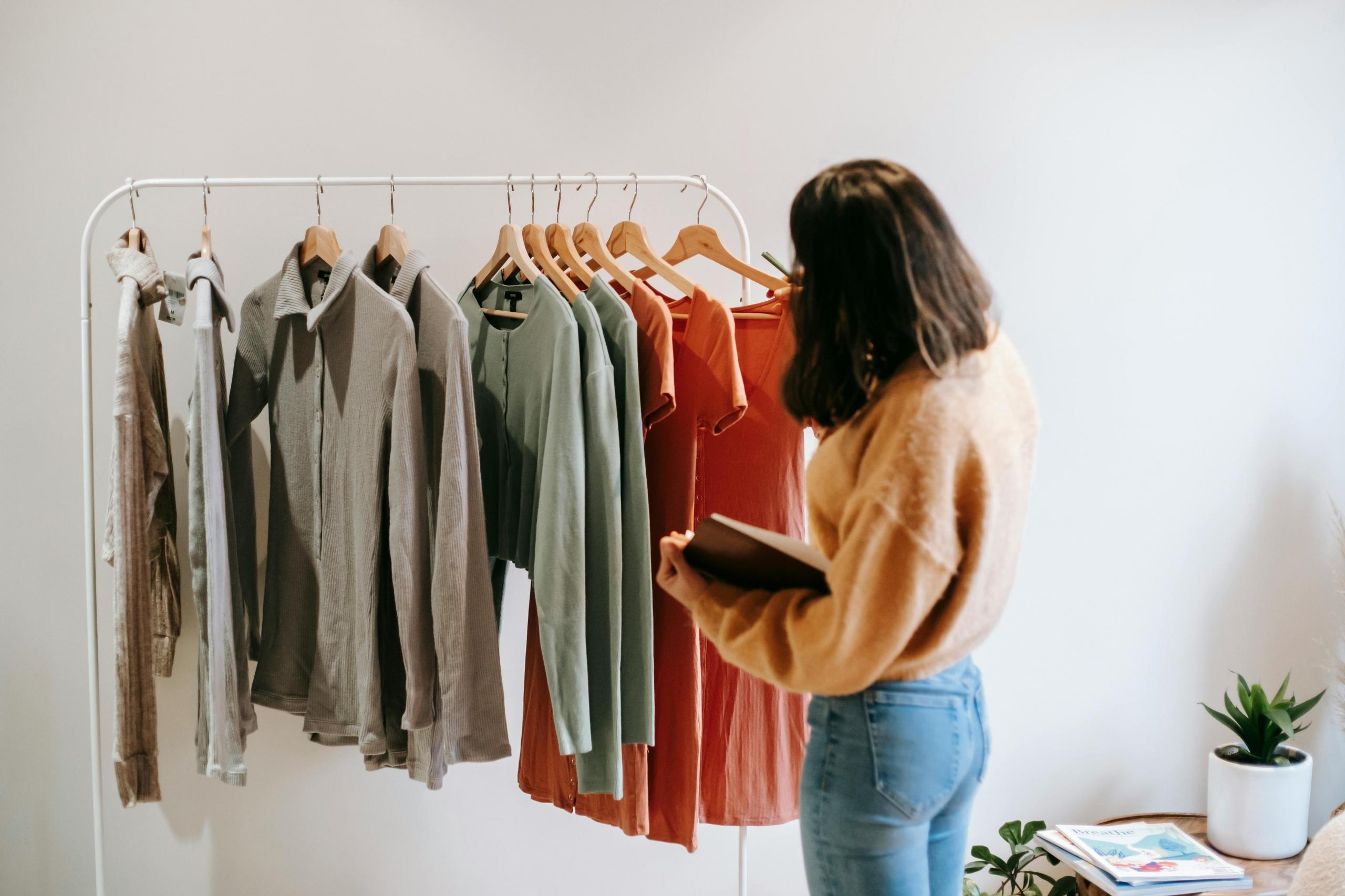 woman sorting clothing on rail in clothing shop