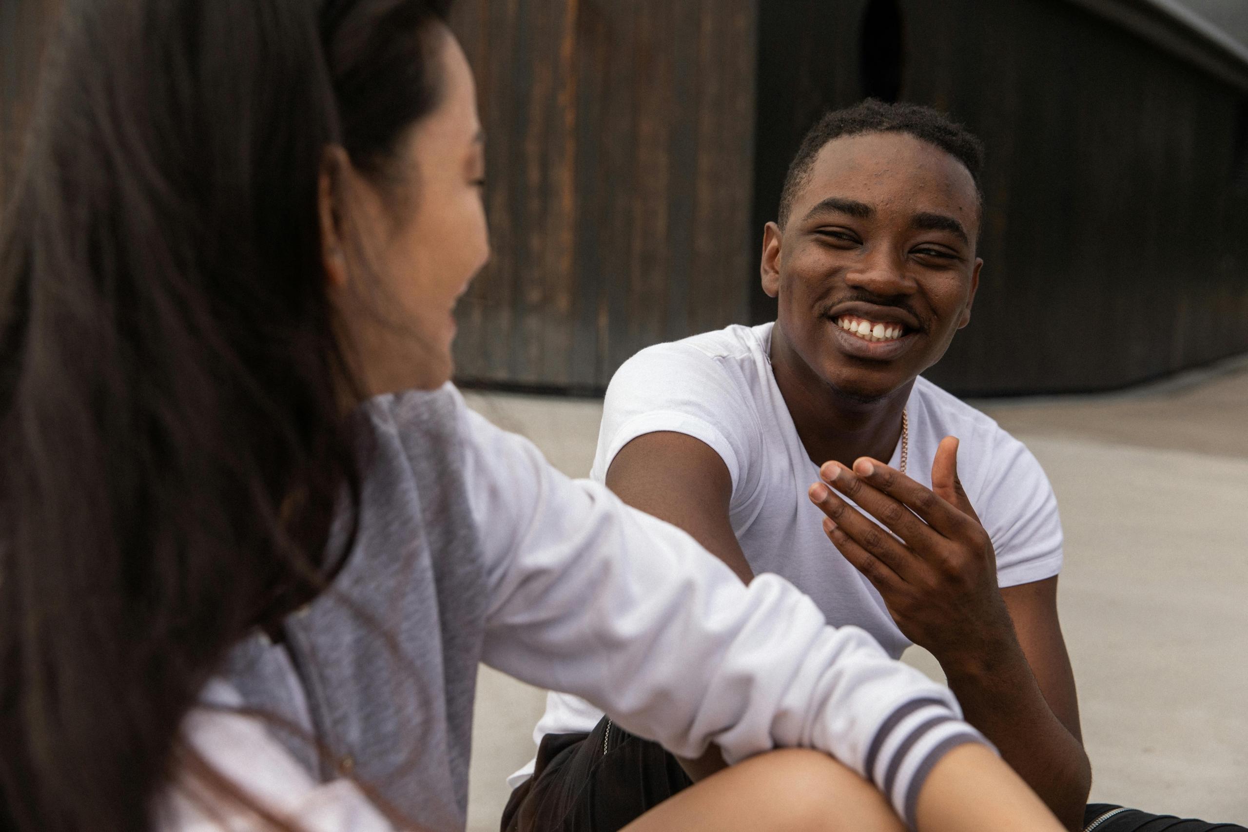 woman and man seated on ground outdoors laughing