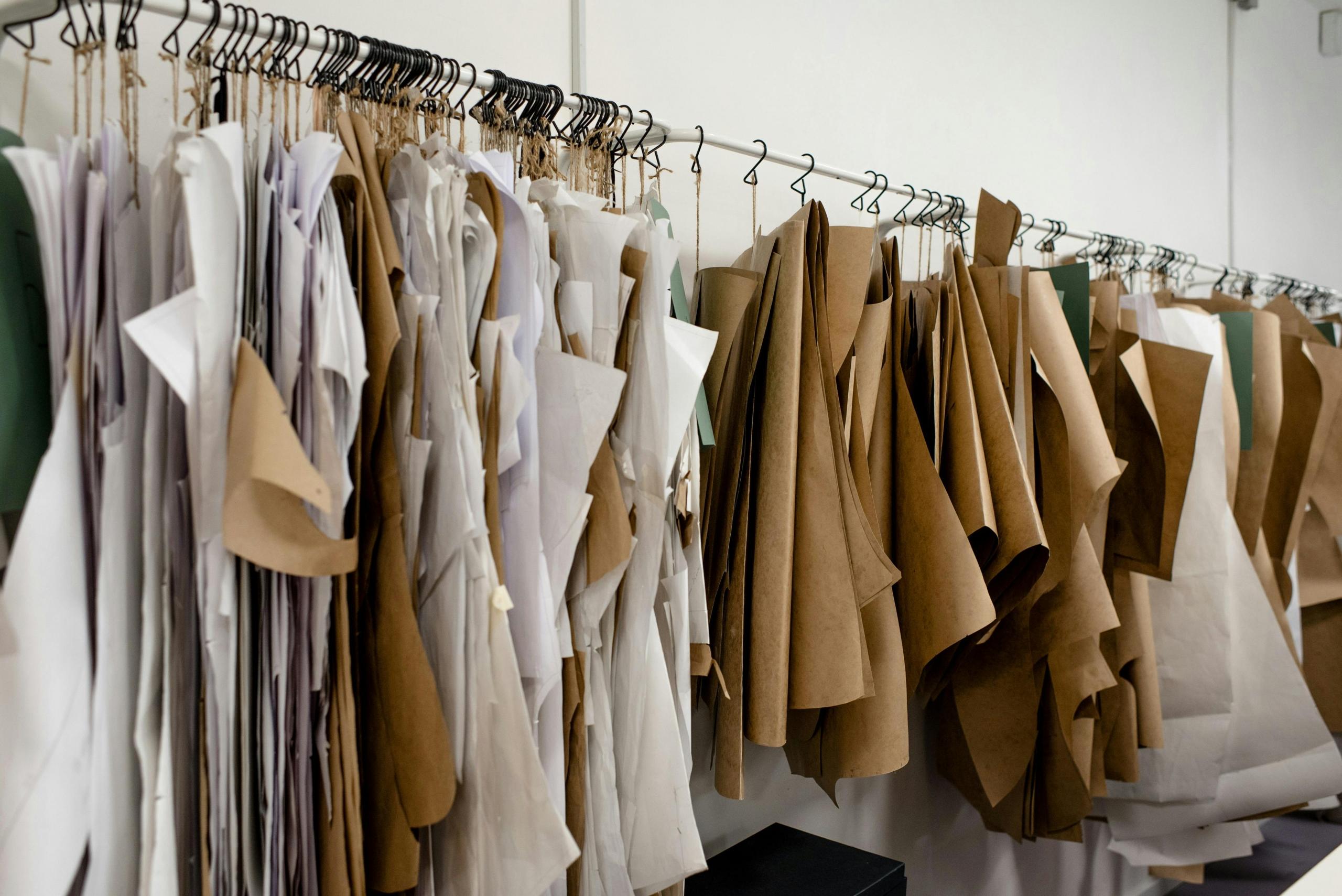 sheets of brown paper with clothing patterns hung on a rail